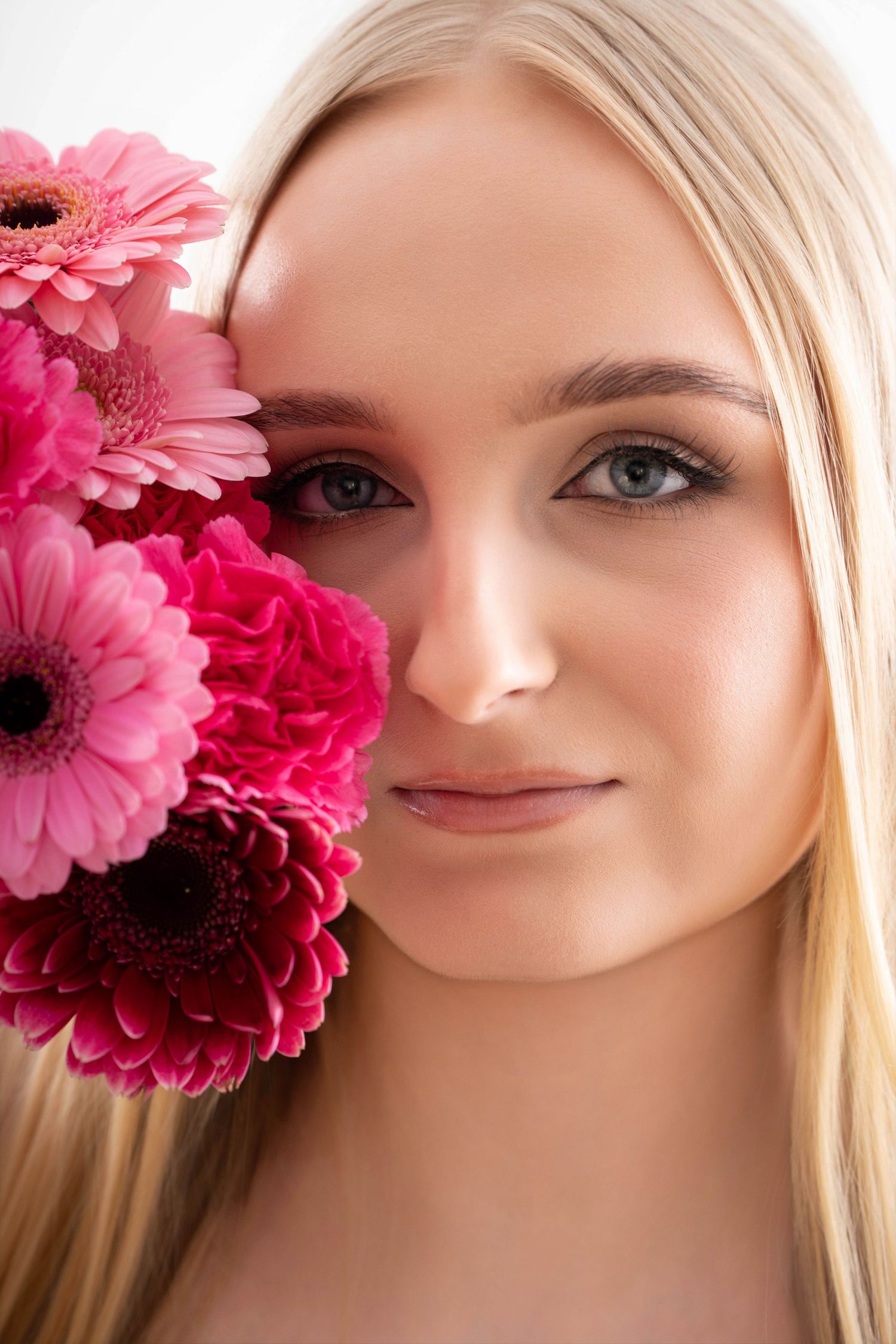 A series of artistic beauty portraits with pink gerbera daisies and soft lighting creating a romantic spring aesthetic.
