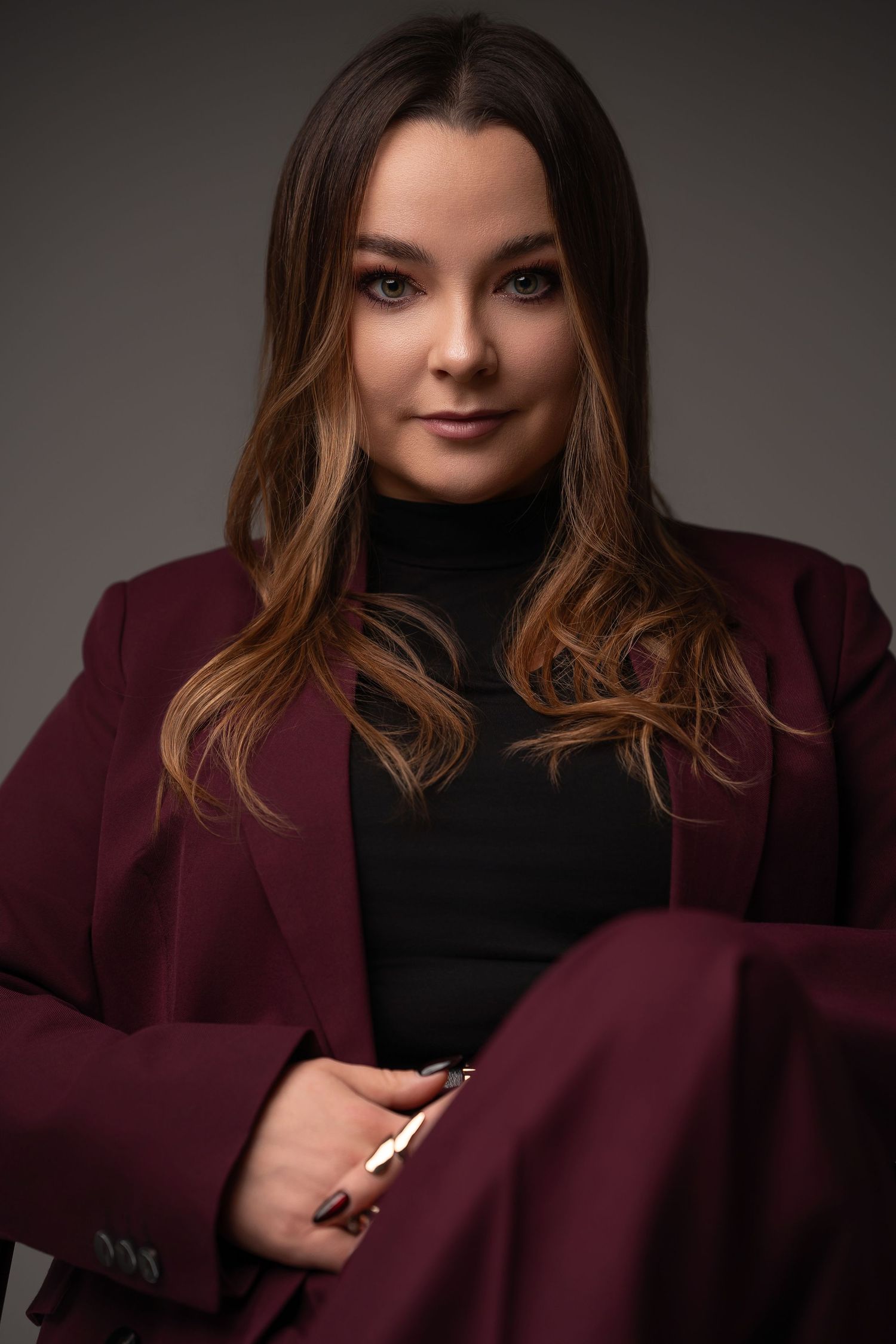 Professional studio portrait series showing a model in a burgundy blazer and black top against a dark background.