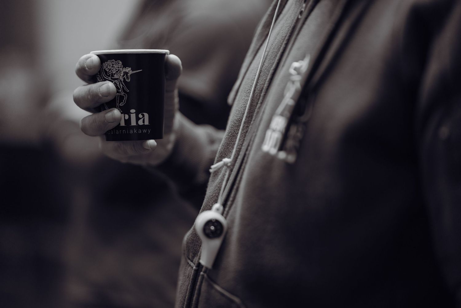 Sesja produktowa, kubek kawy z logo, czarno-białe, mocny bokeh.