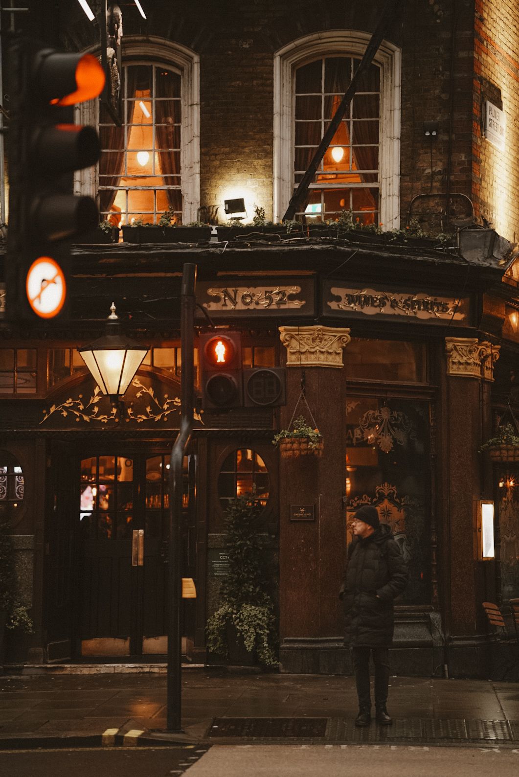Historic pub exterior with glowing windows and traditional lanterns in London at night.