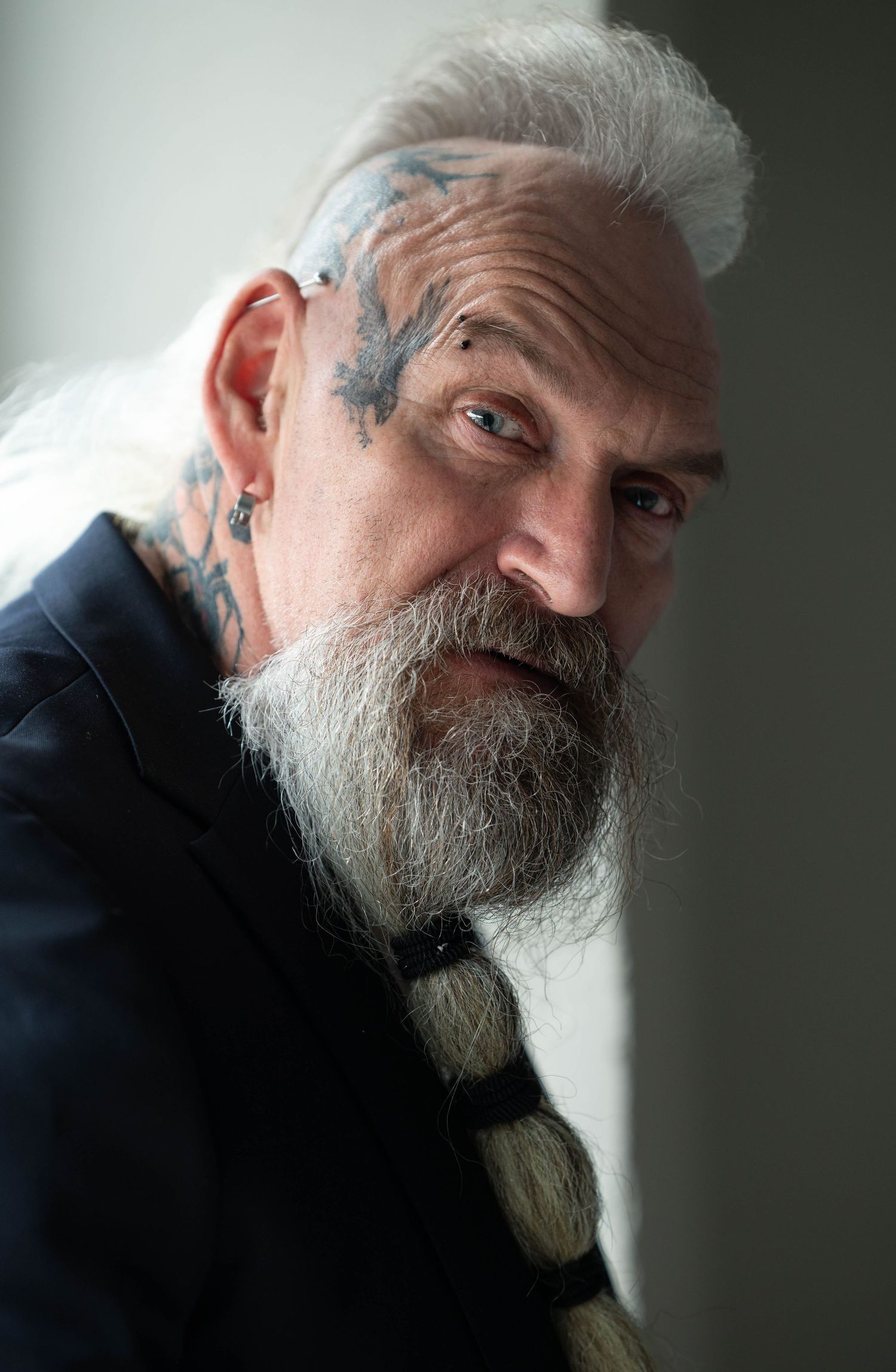 Moody side-profile portrait showing detailed facial features and braided beard in natural light.
