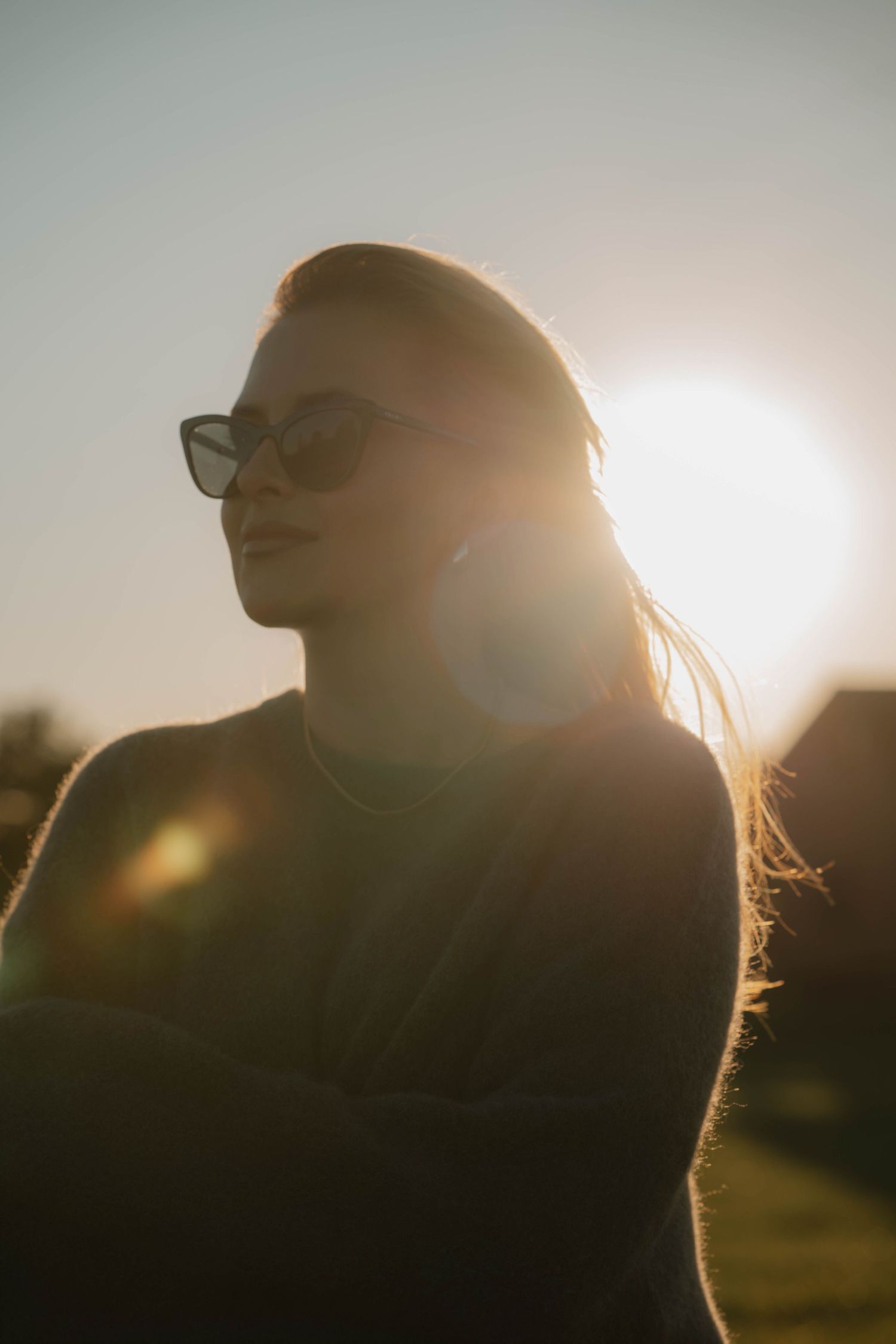 Silhouette of person wearing glasses against golden sunlight creating a warm backlit glow at sunset.
