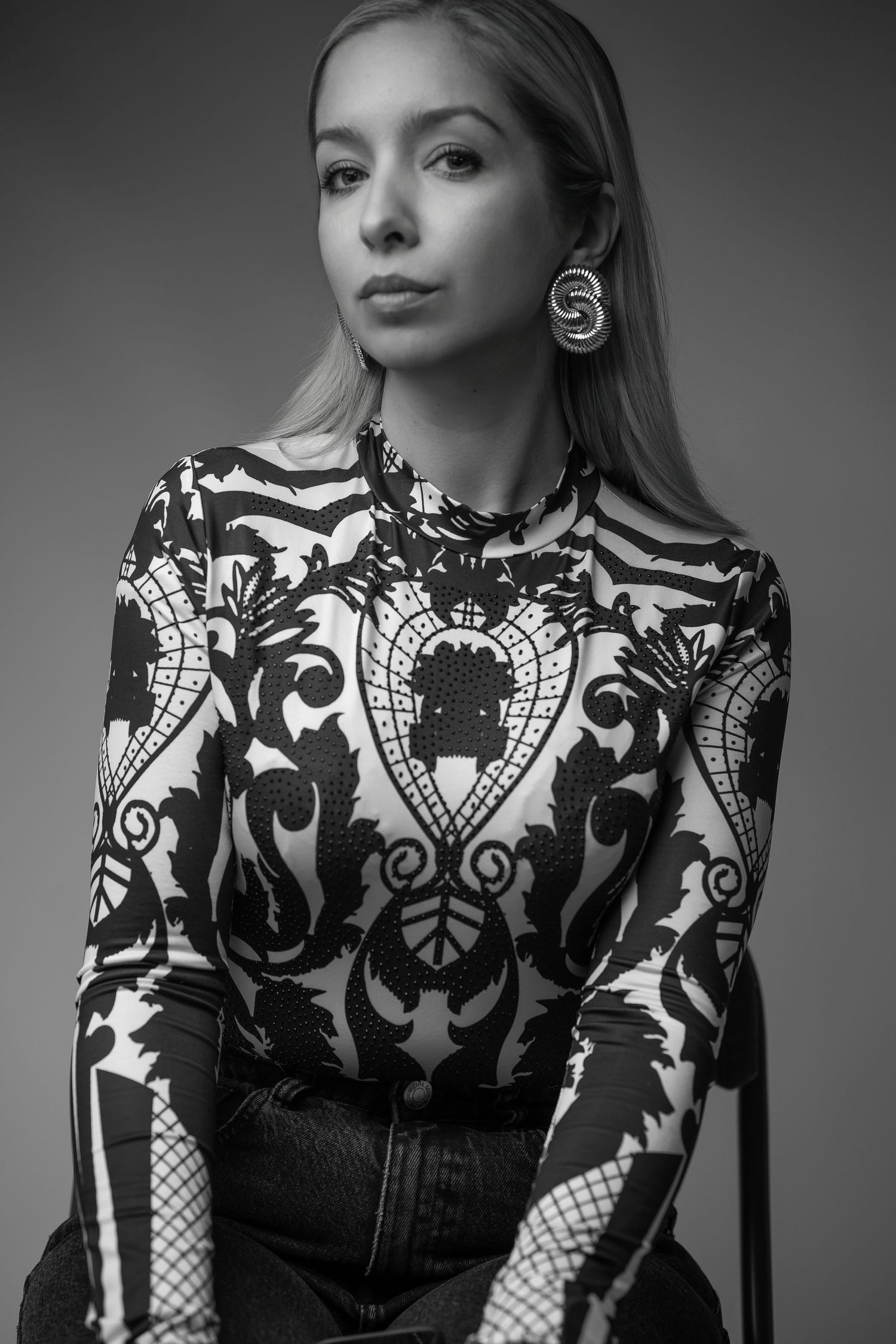 Fashion model poses in striking black and white patterned bodysuit with intricate geometric and floral designs.