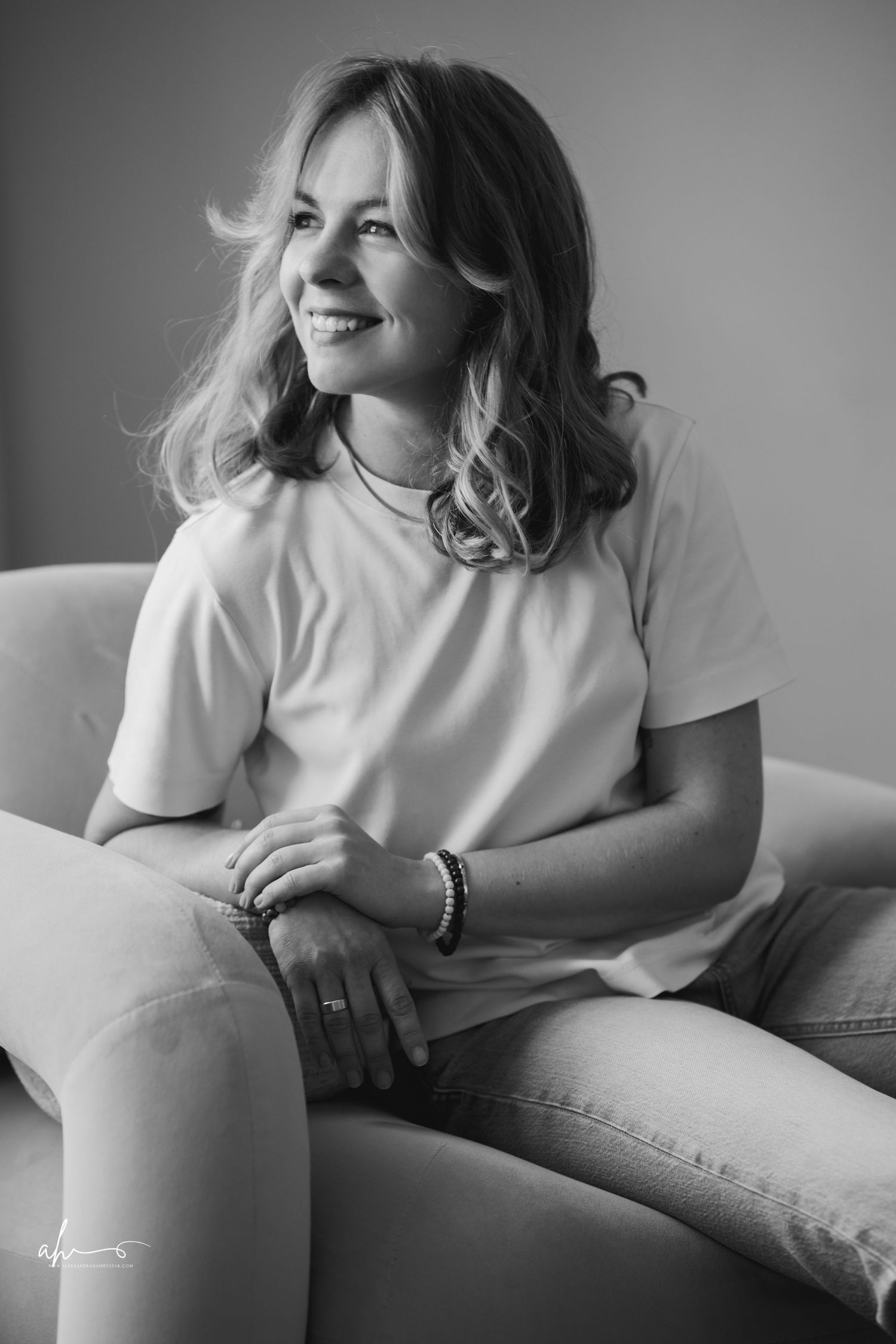 A candid black and white portrait of someone sitting casually on a couch in a white t-shirt.