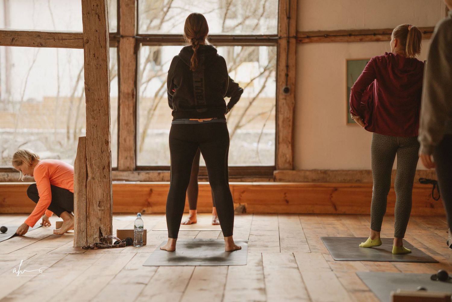 Three people exercising together in a rustic wooden room with large windows during a fitness class.
