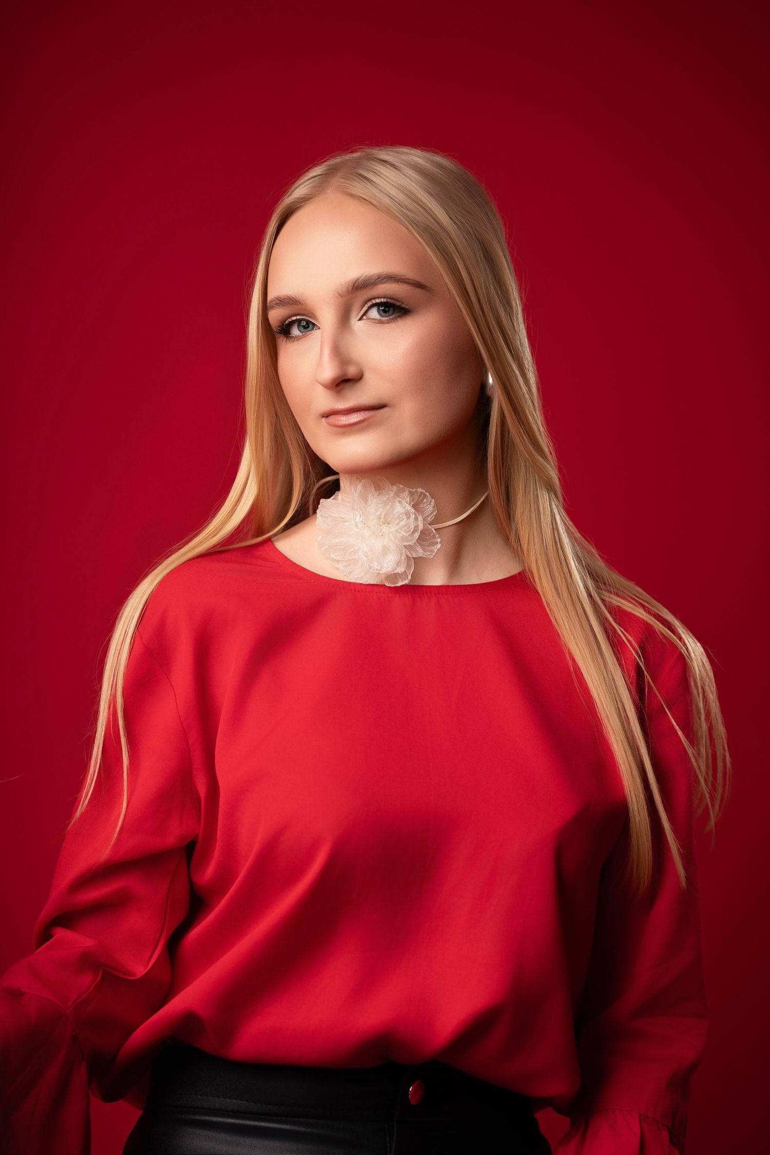 Fashion portrait against red background with dramatic lighting and flowing red blouse.