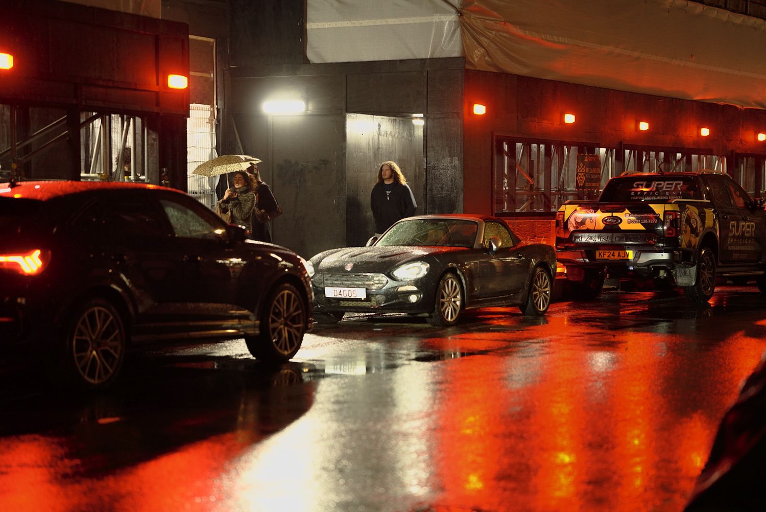 Cars parked in a dimly lit garage with red ambient lighting creating dramatic reflections.