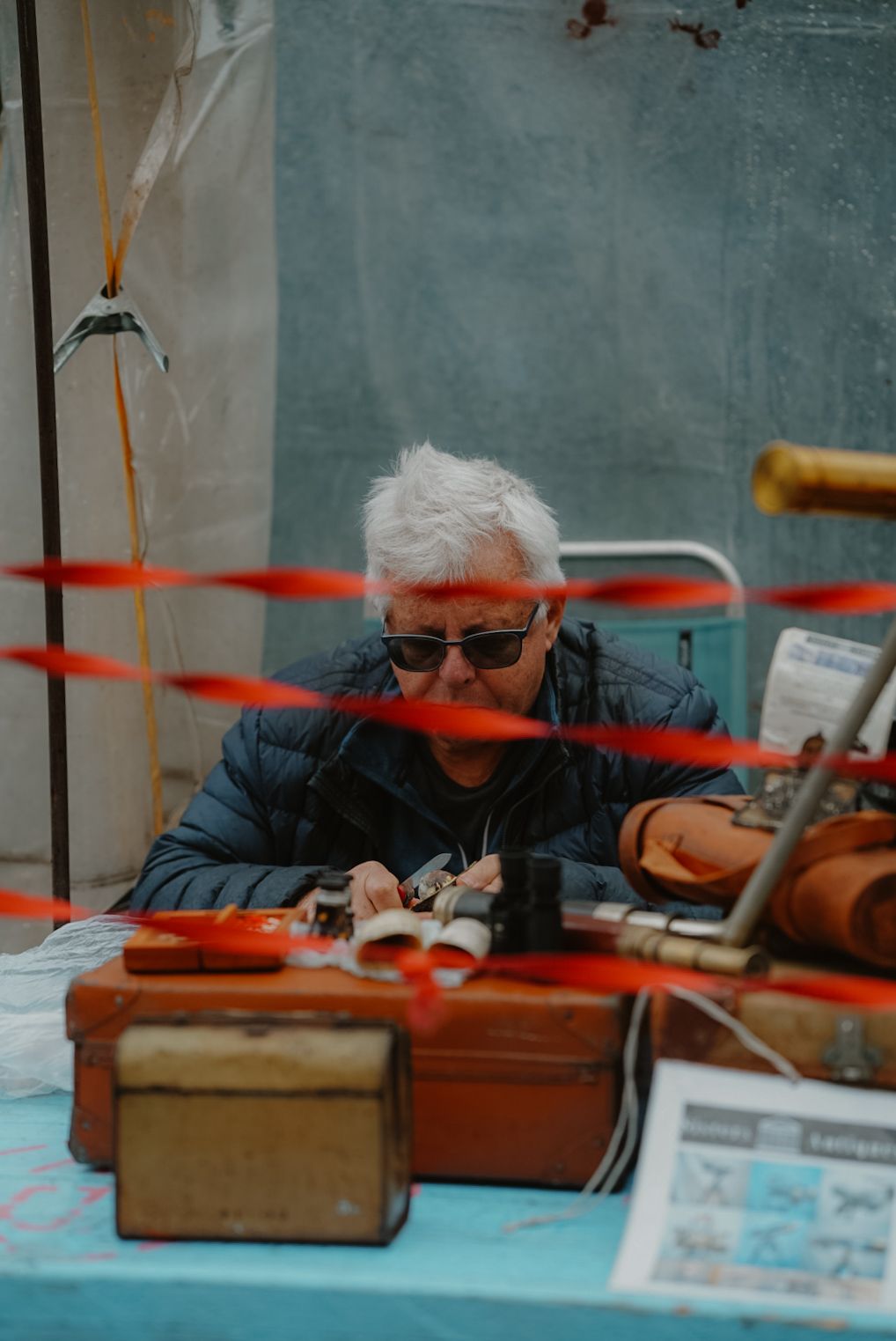 An artisan works on detailed repairs at a workbench with red tools and equipment.