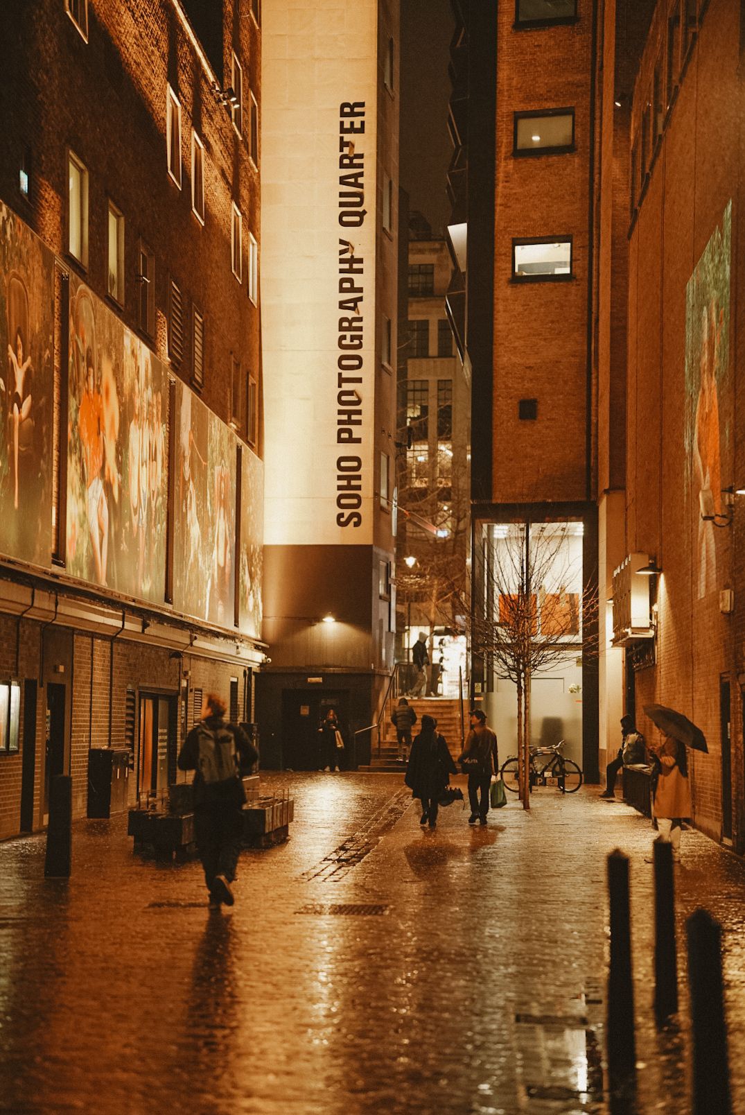 Urban alley with illuminated signs and brick buildings on a rainy night.