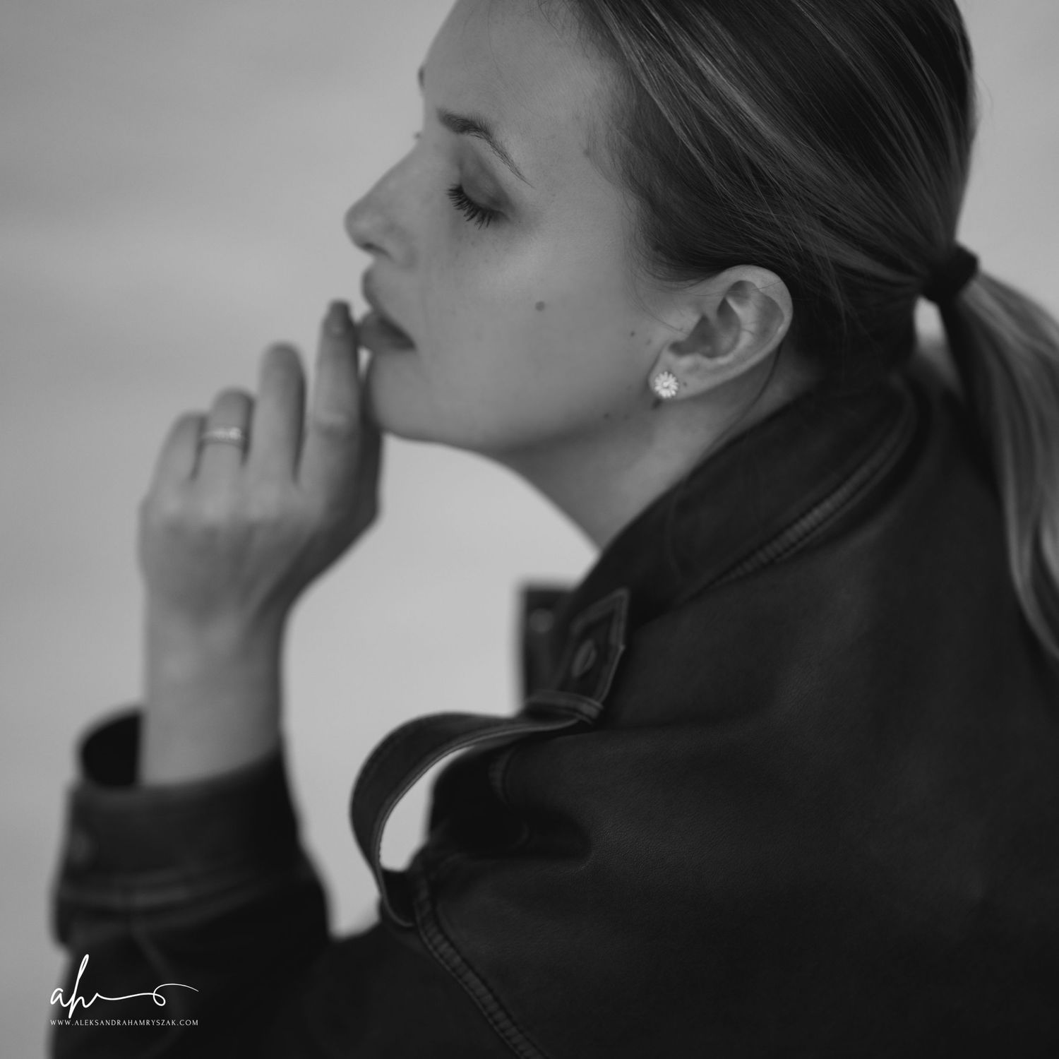 Black and white portrait profile with elegant pose showing contemplative side view against light background.