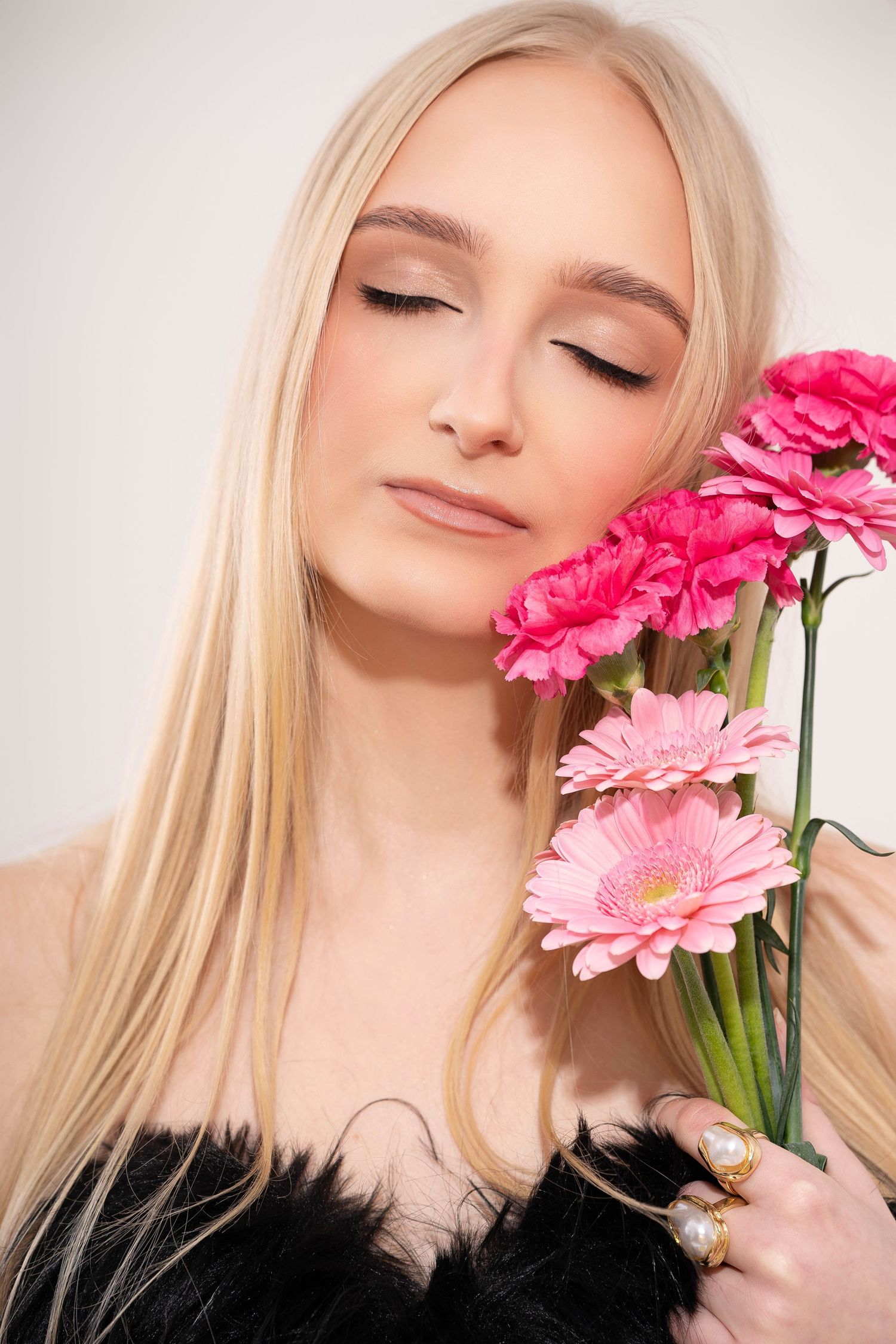 Artistic portrait series with pink gerbera daisies against light background showing dreamy expressions and blonde hair.