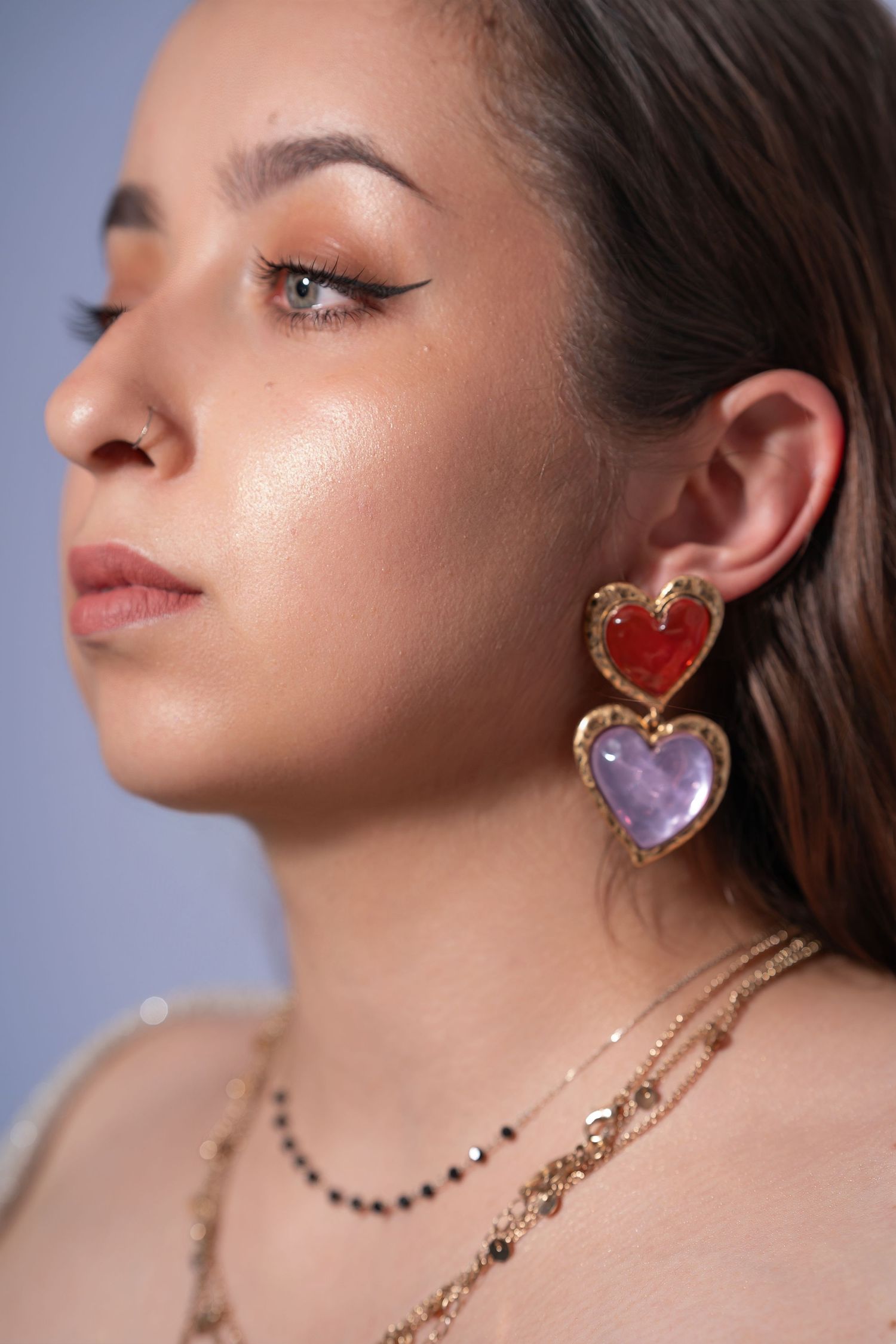 Close-up fashion jewelry photo series showing heart-shaped gemstone earrings and delicate necklaces against a blue backdrop.