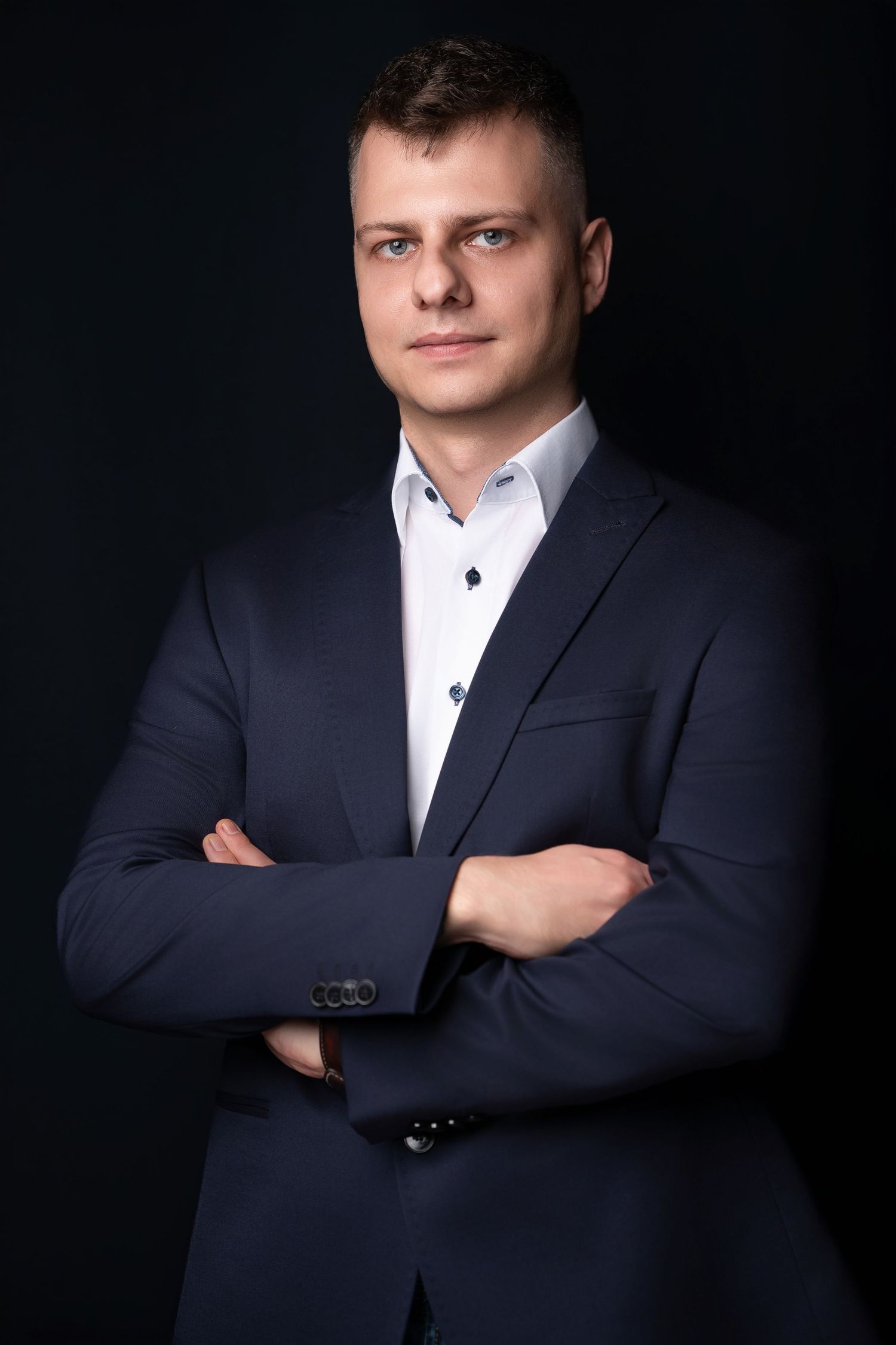 Professional business portrait series against dark background showing confident pose with crossed arms in navy suit.