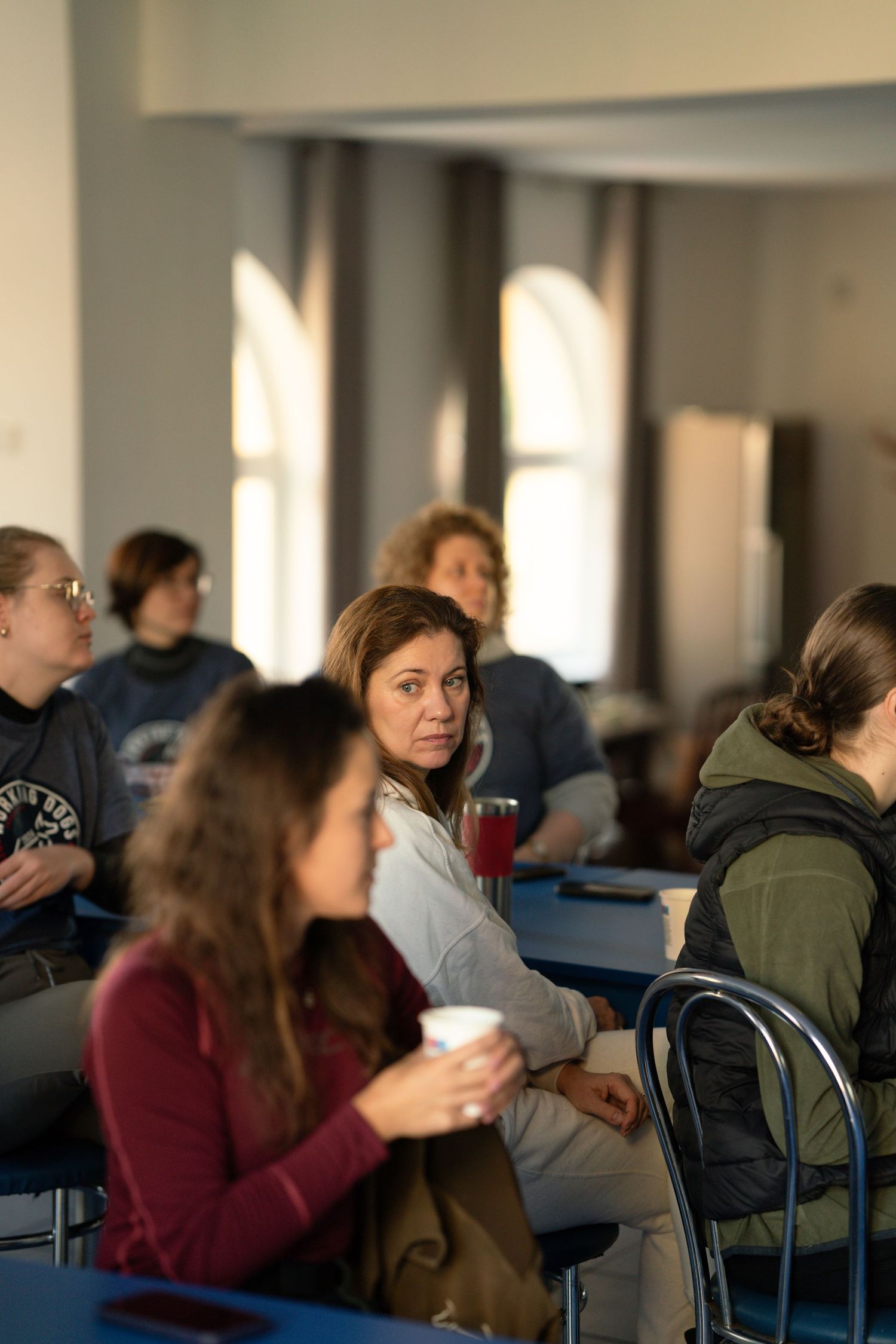 Students attending a classroom lecture in a sunlit room with large windows.