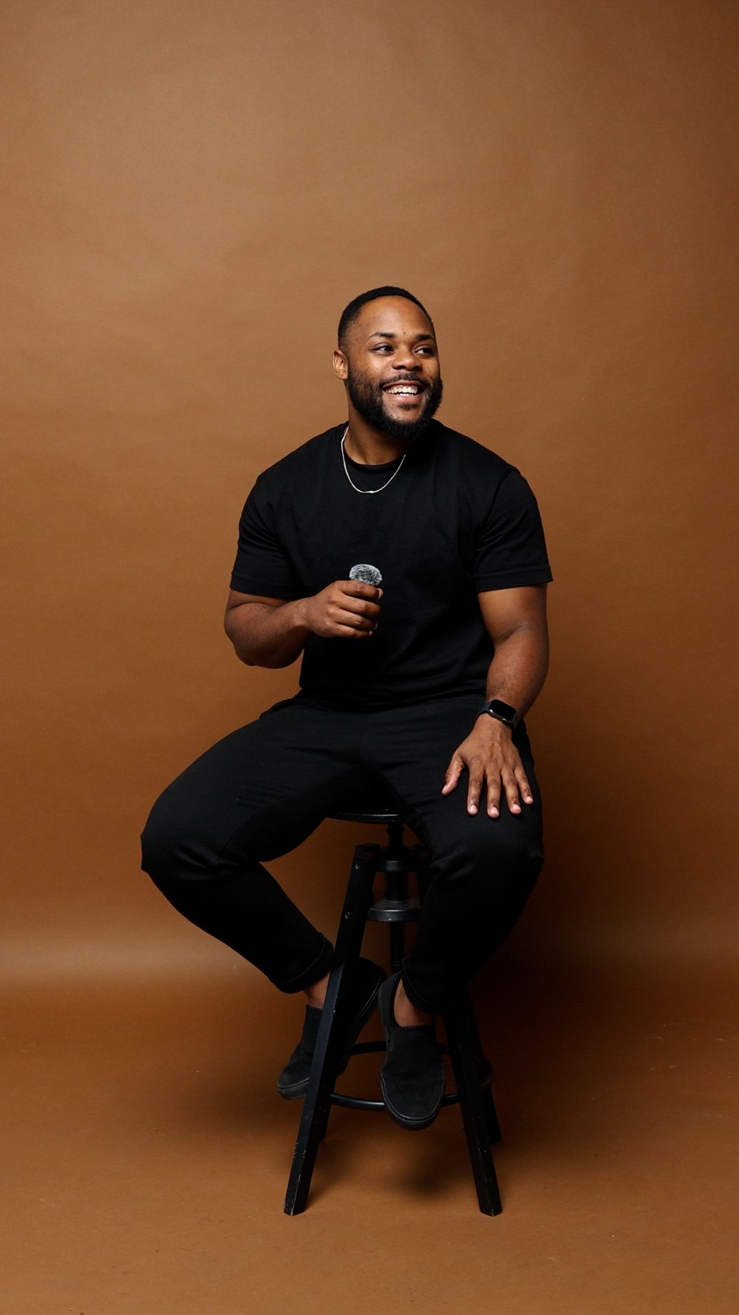 A person in a black t-shirt and pants sits on a stool against a brown backdrop in a series of dynamic poses.