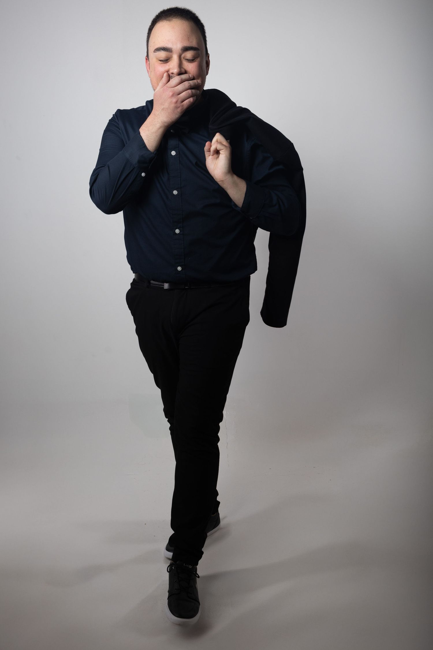 Person in all black clothing poses dramatically against gray background in sequence of expressive movements.