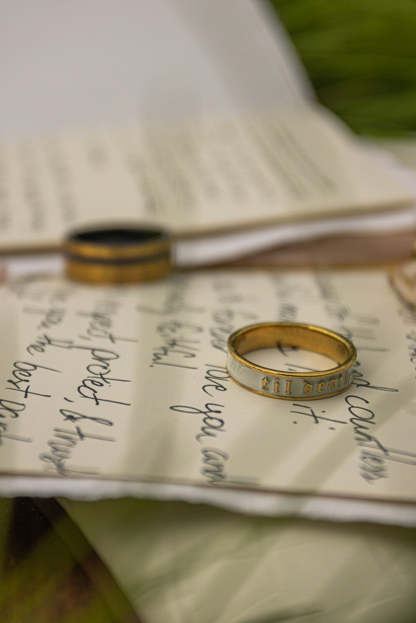 Wedding rings and handwritten vows on textured paper in natural light.