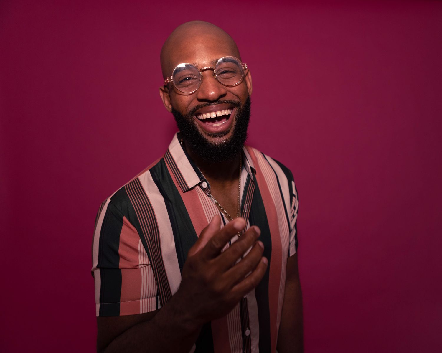 Portrait of joyful person in striped shirt against burgundy background.