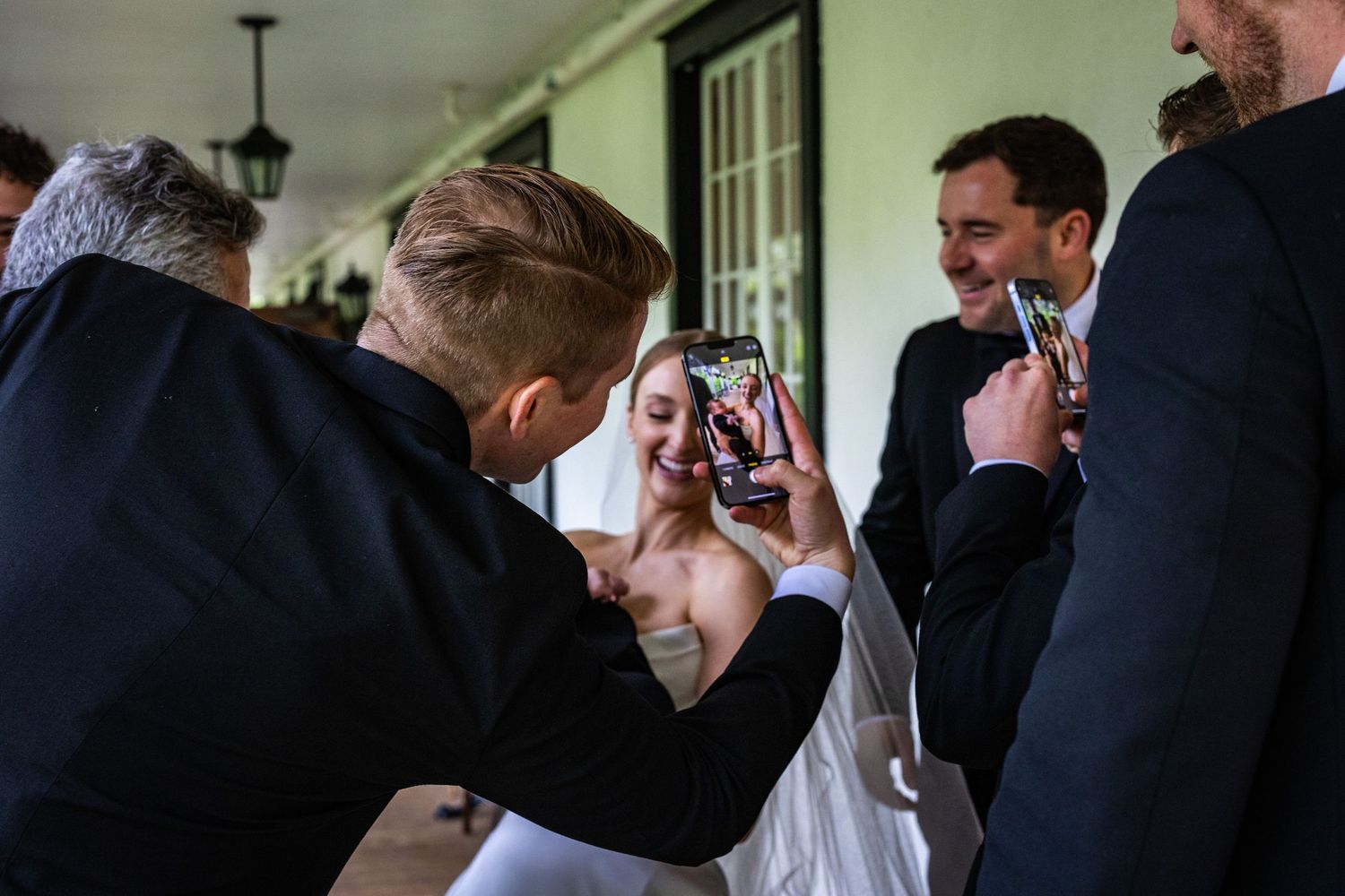 A bride and groom share an intimate moment during their wedding celebration while guests look on in the background.
