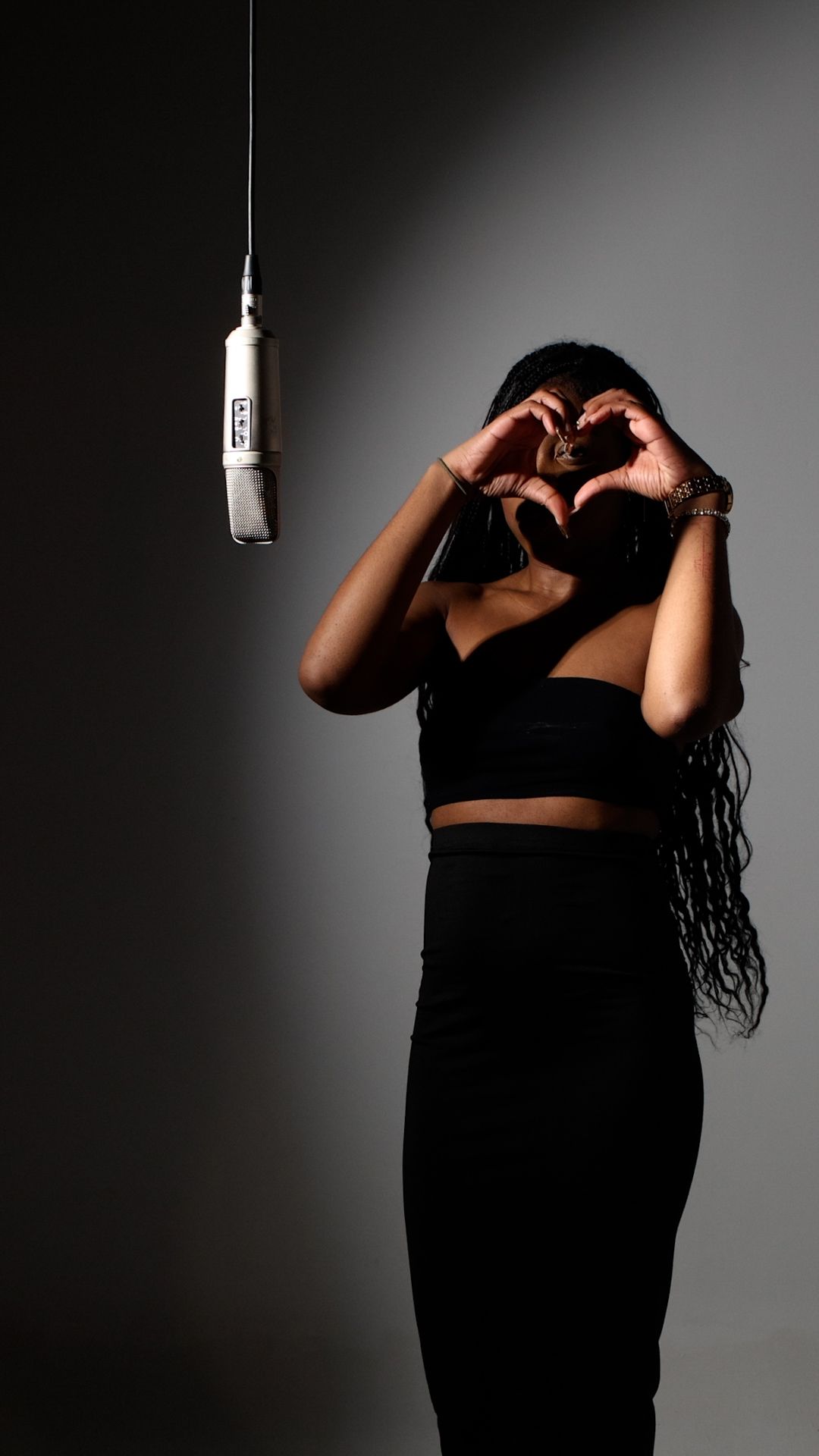 A dramatic black and white photo series showing a figure in silhouette making heart shapes with their hands against a light.