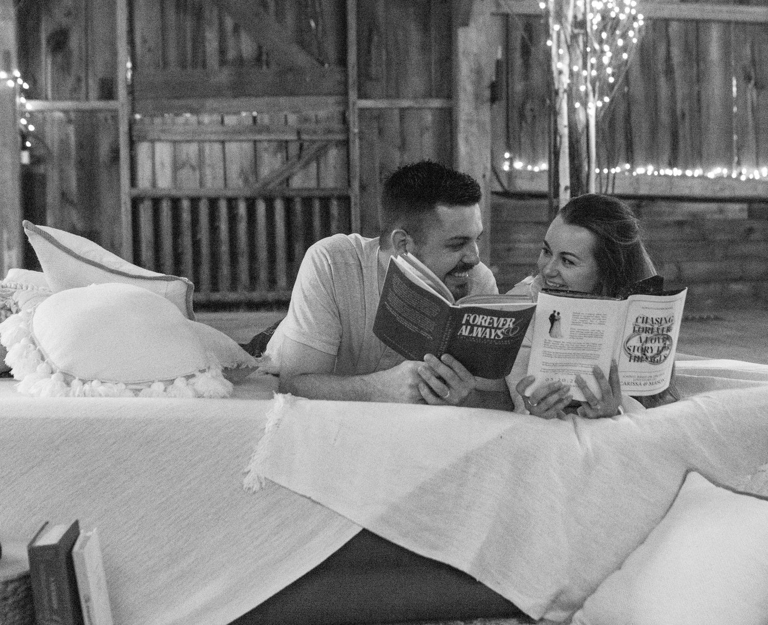 A black and white photo of a shared reading moment on white linens.