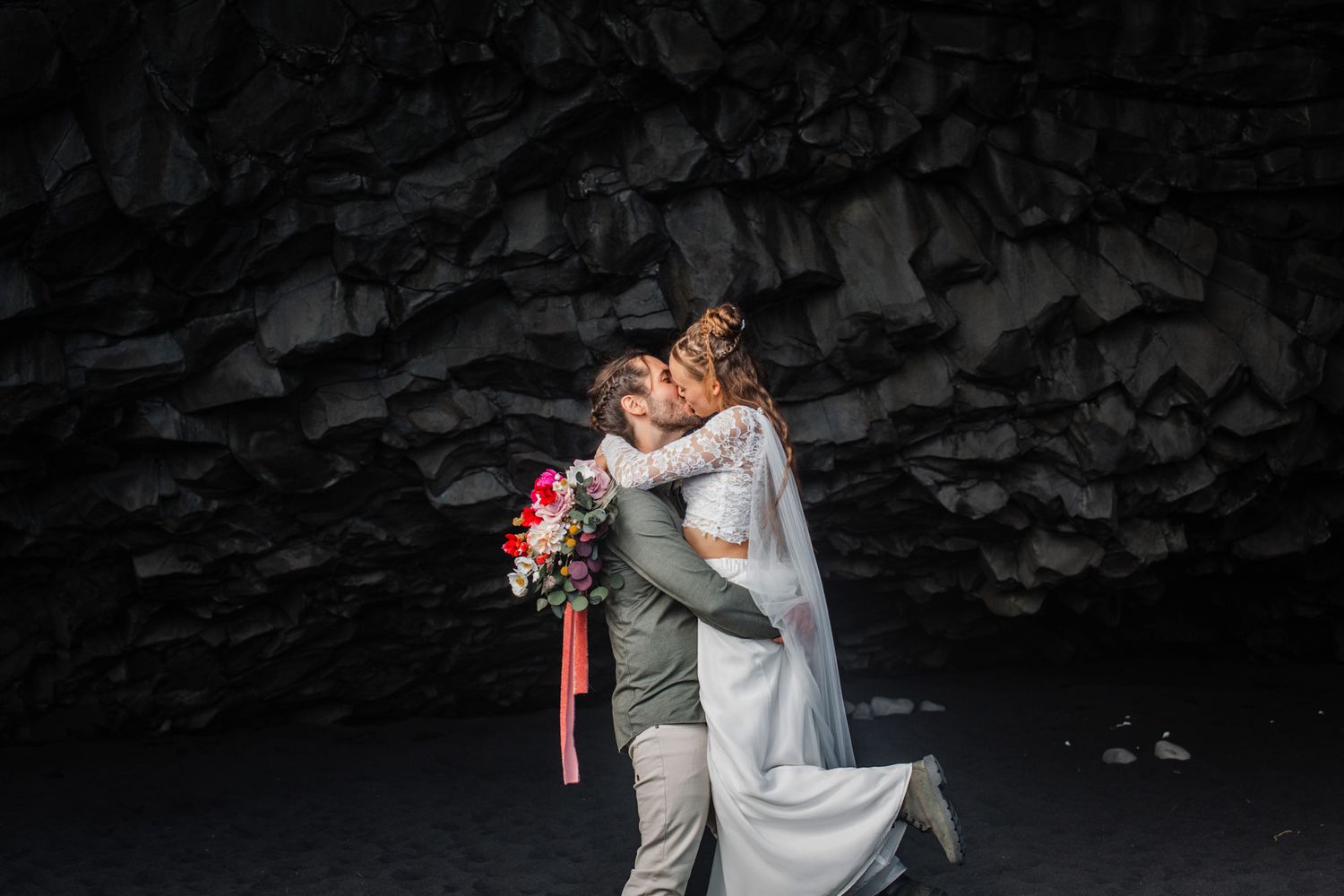 A romantic moment captured inside a dark volcanic cave with dramatic lighting.