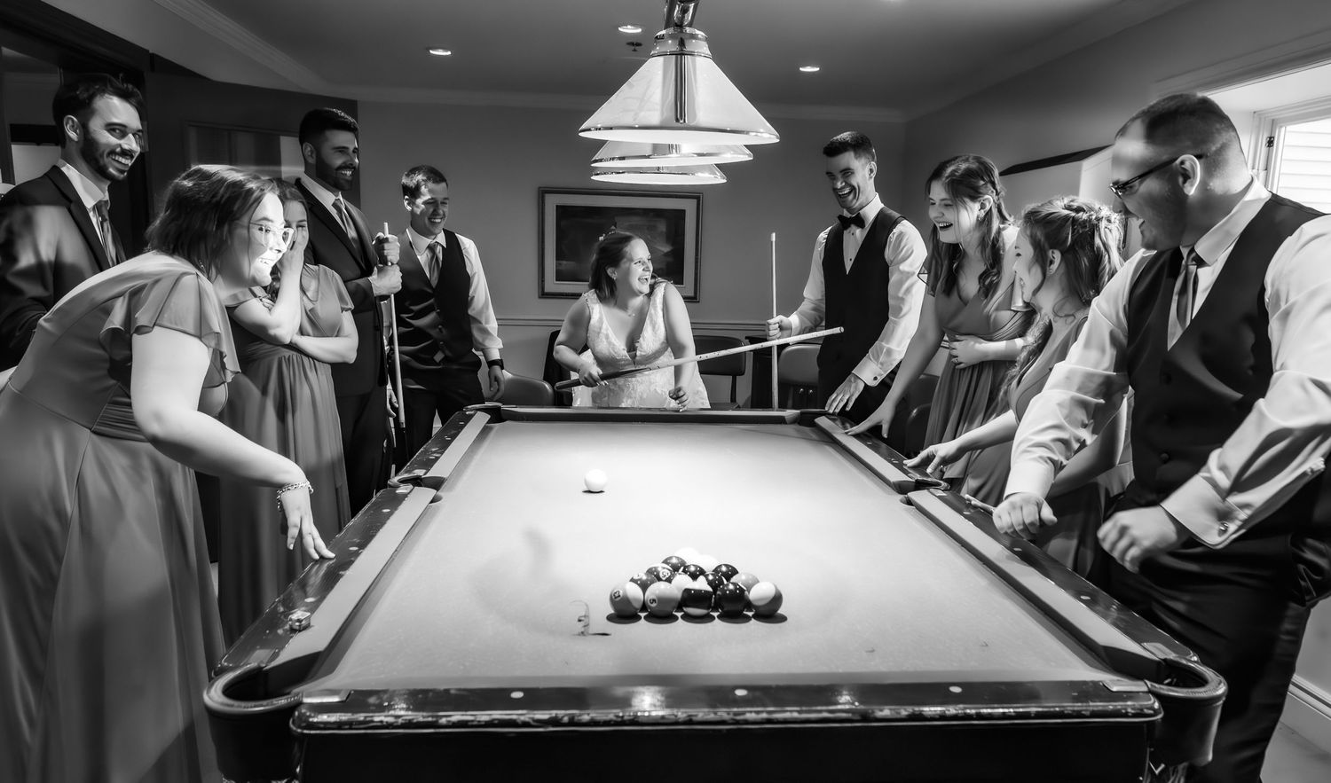 People playing pool at a billiards hall in black and white photography.