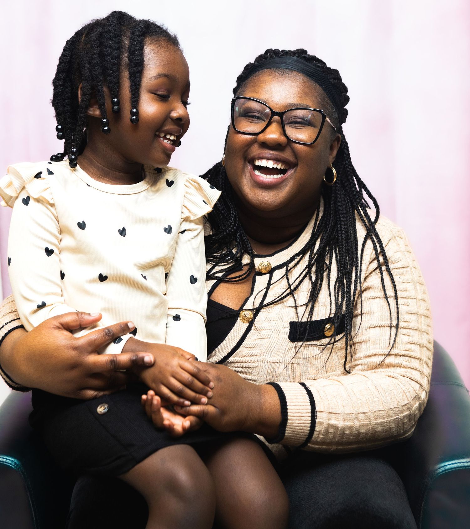 A joyful moment shared between two people wearing sweaters as they laugh together on a couch.