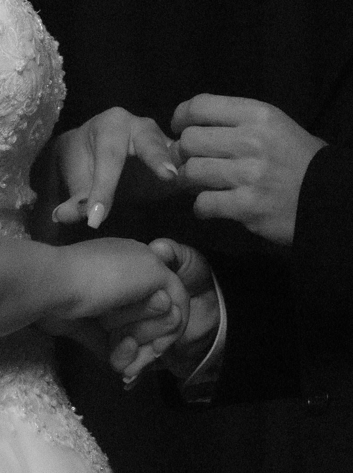 Close-up black and white images showing hands exchanging wedding rings during a ceremony.