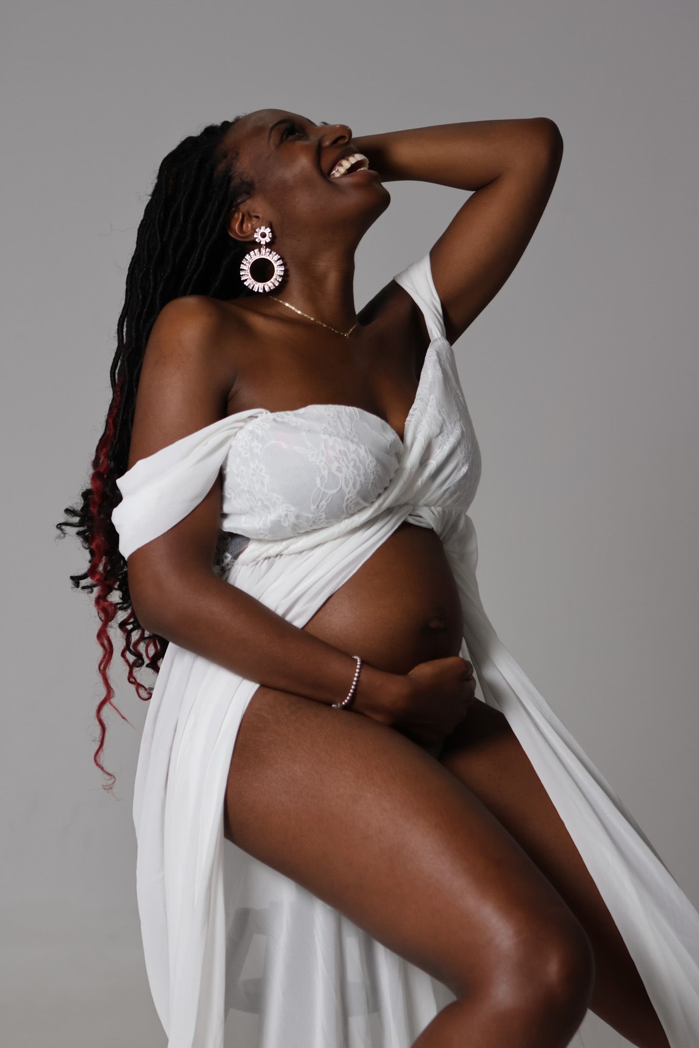 Artistic portrait of person in white draped fabric with statement earrings.