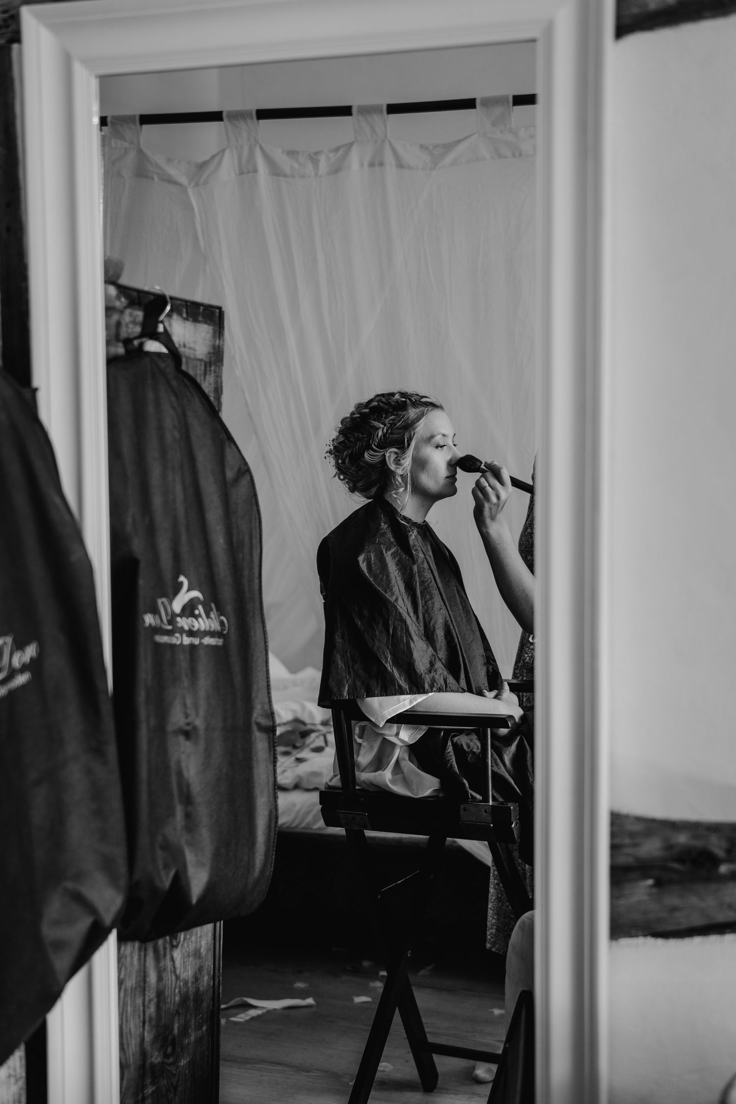 Black and white photograph showing various coats and garments hanging in a backstage dressing room area.