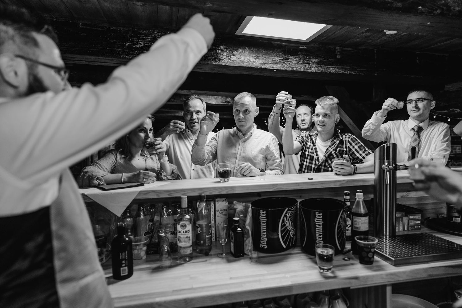 Black and white photo of beer bottles lined up on a bar counter at a reception event.