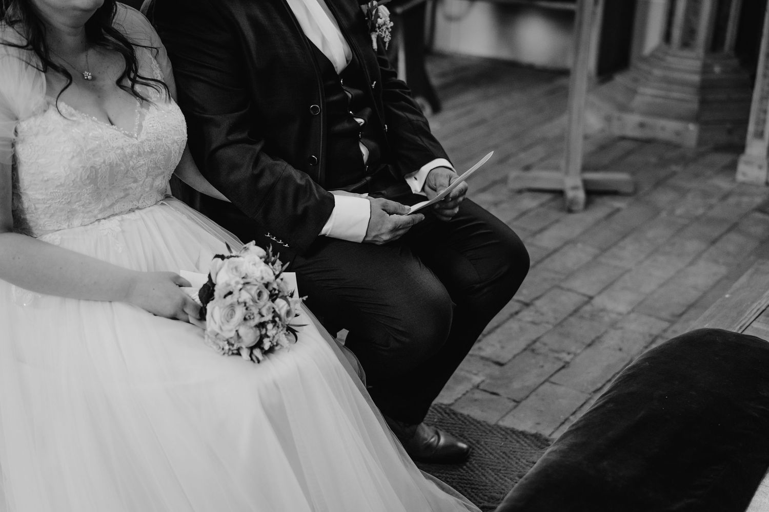 Black and white photo showing wedding details with a bouquet and formal attire.