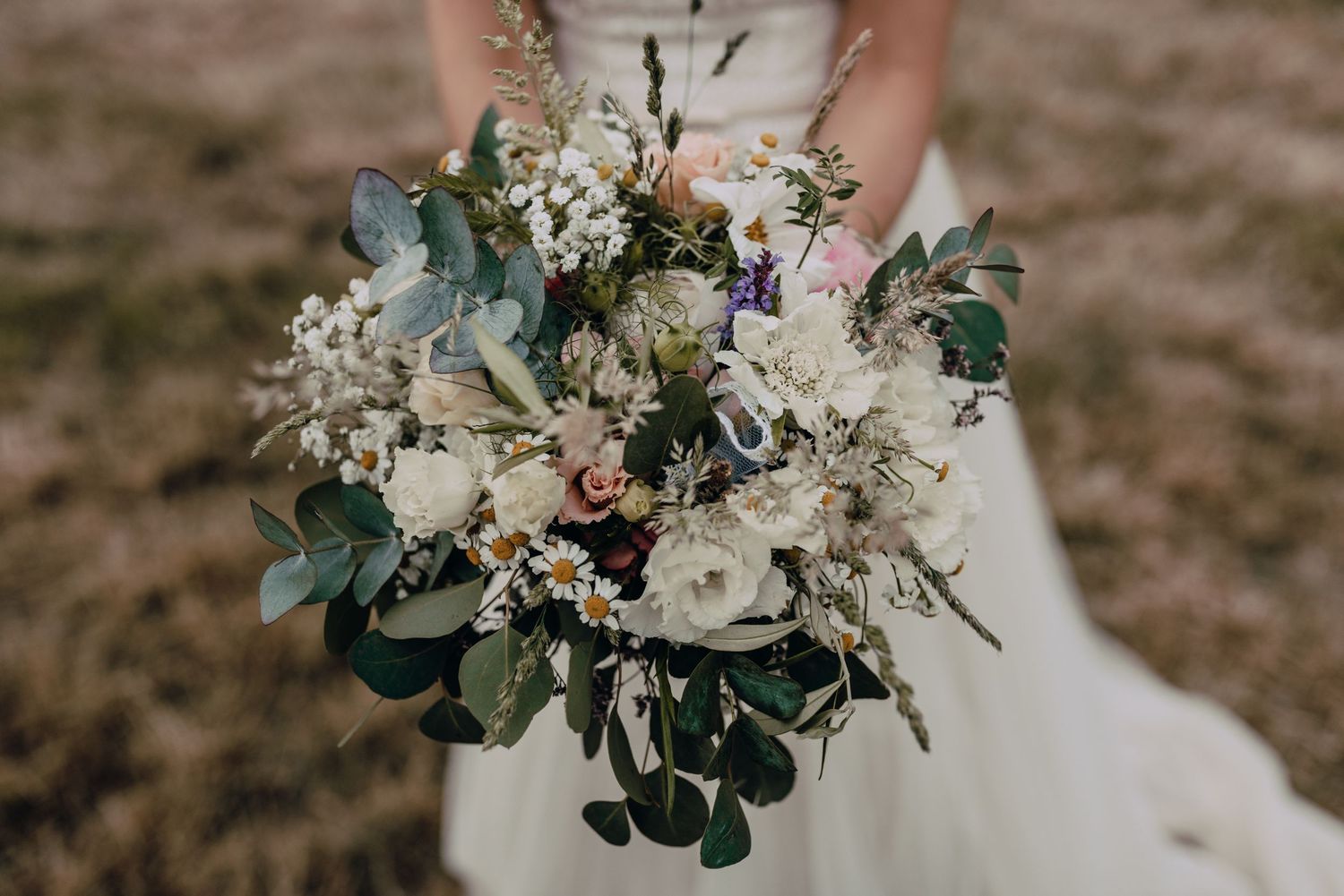 Delicate white and green wedding bouquet with eucalyptus leaves photographed in natural light.