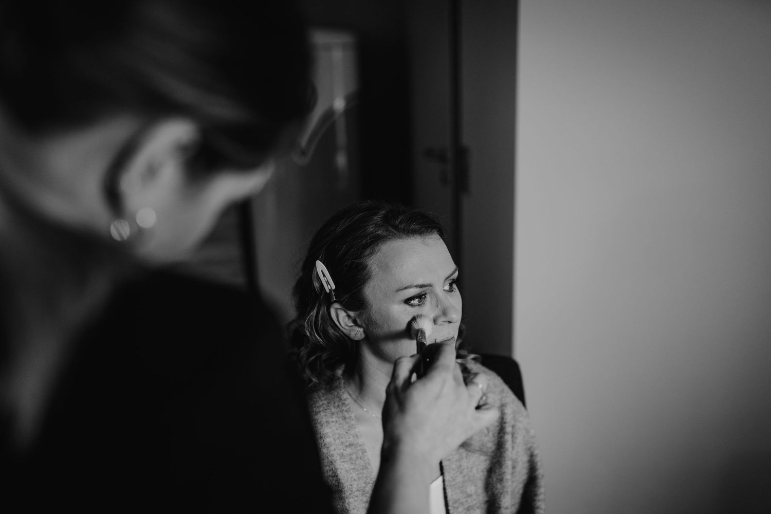 A makeup artist applies mascara to a model's eye during a beauty preparation session.