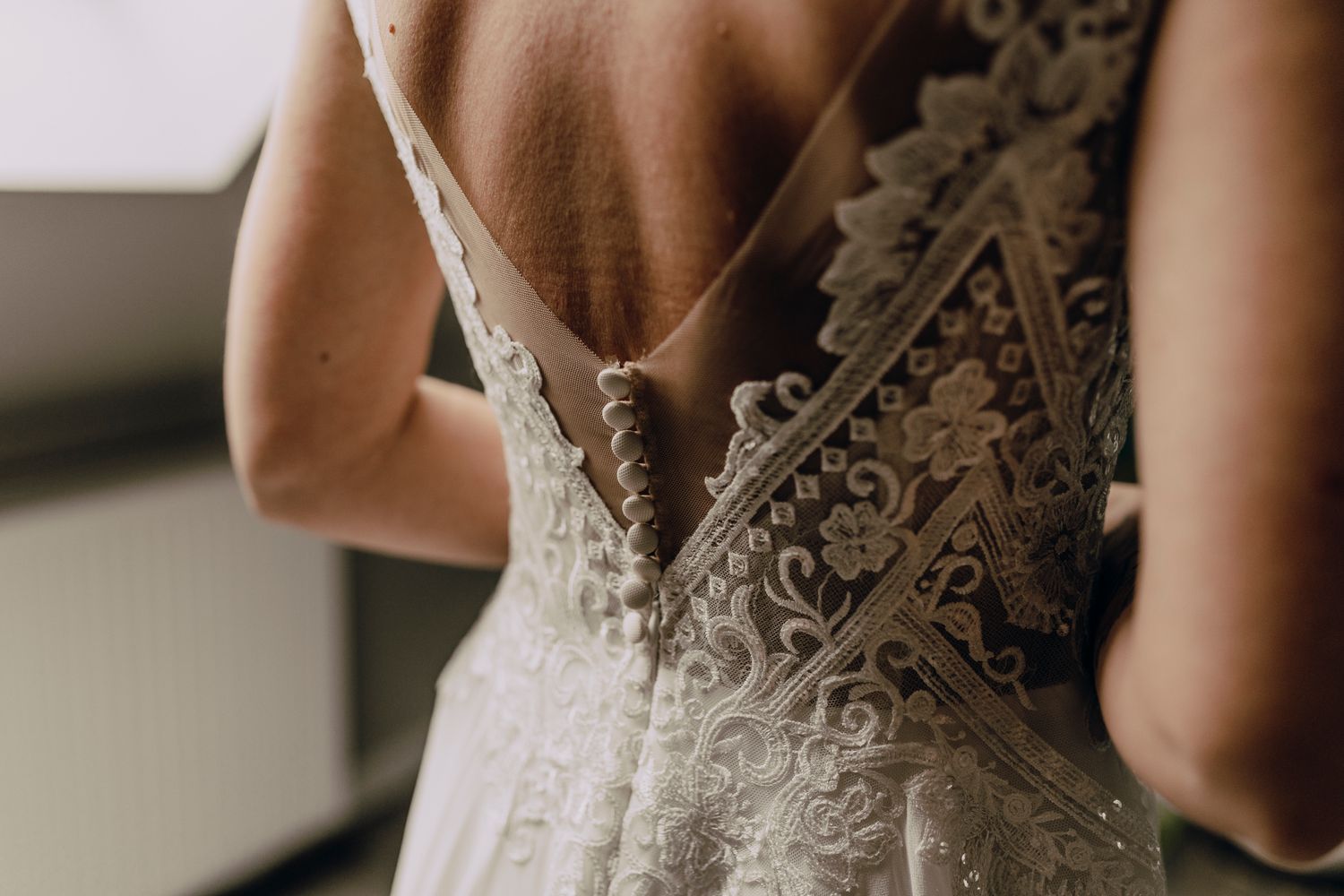 Close up detail of an elegant white lace wedding dress with intricate floral embroidery on the back.