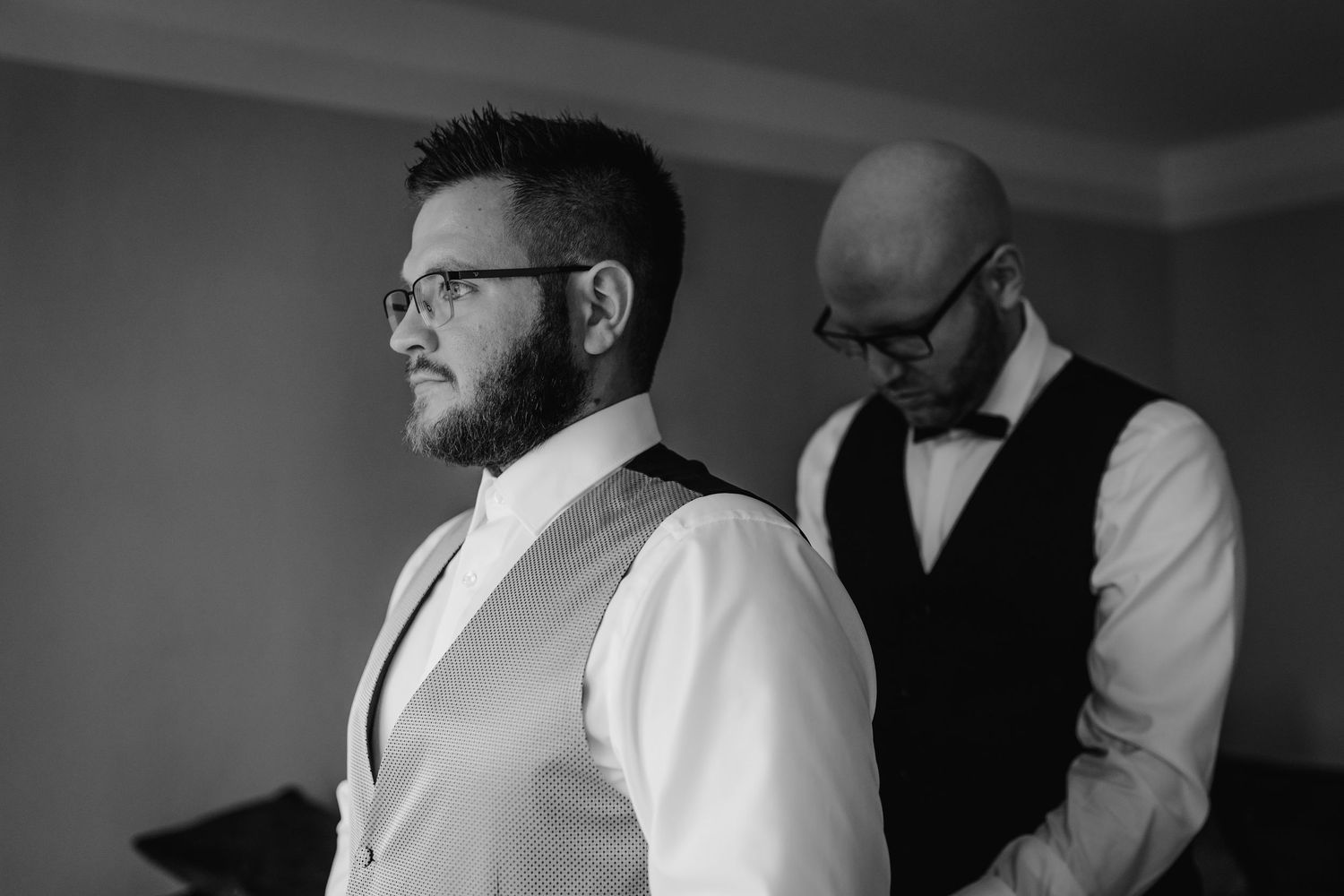 Black and white photo showing people in formal attire hugging at an emotional wedding celebration.