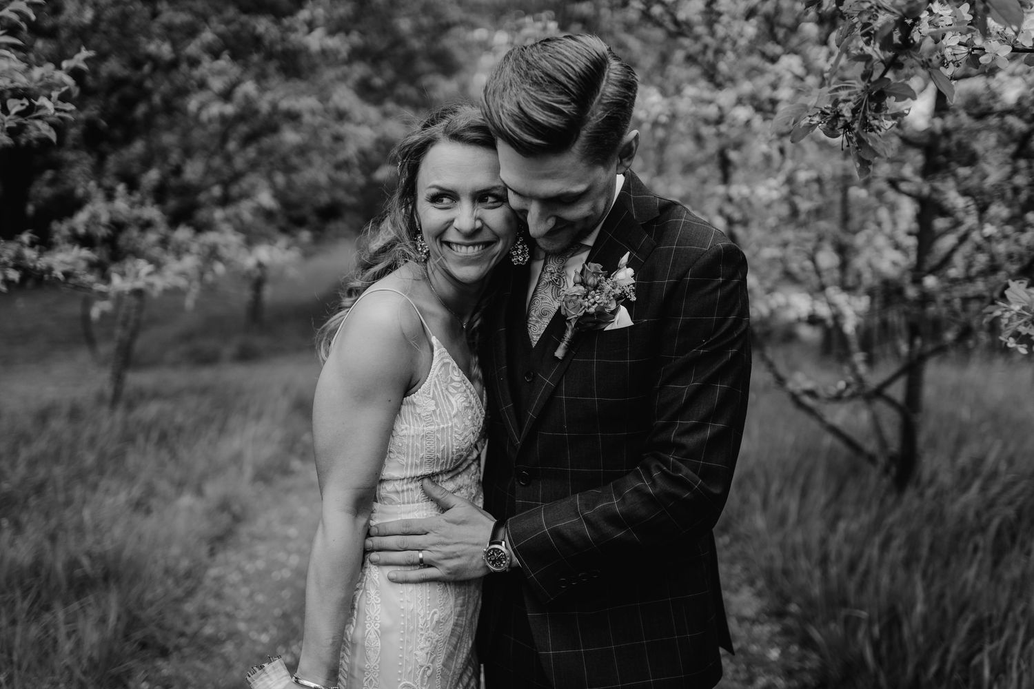Intimate black and white wedding portrait showing couple embracing in a garden setting.