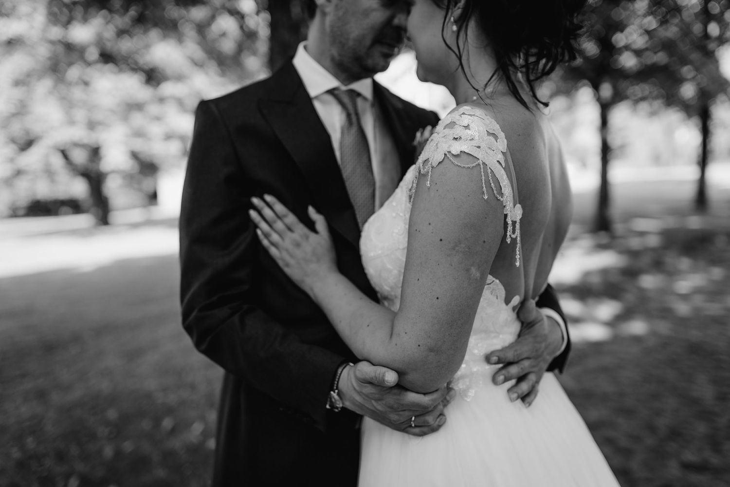 Intimate black and white portrait of newlyweds embracing outdoors.