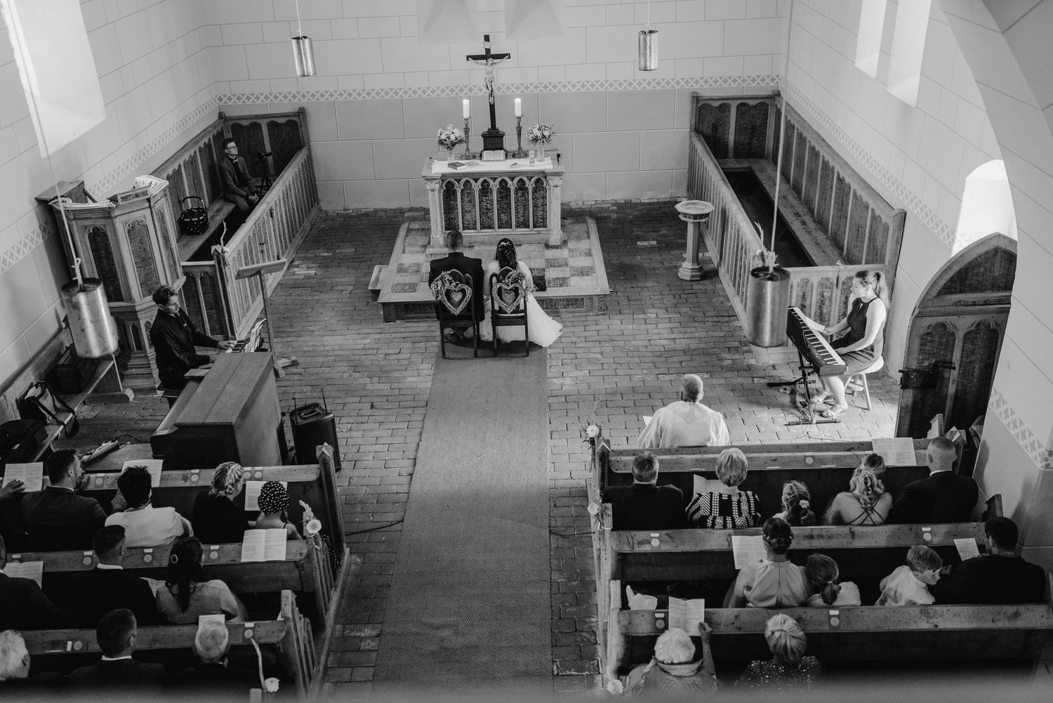 Aerial view of a traditional church ceremony with people seated in wooden pews.