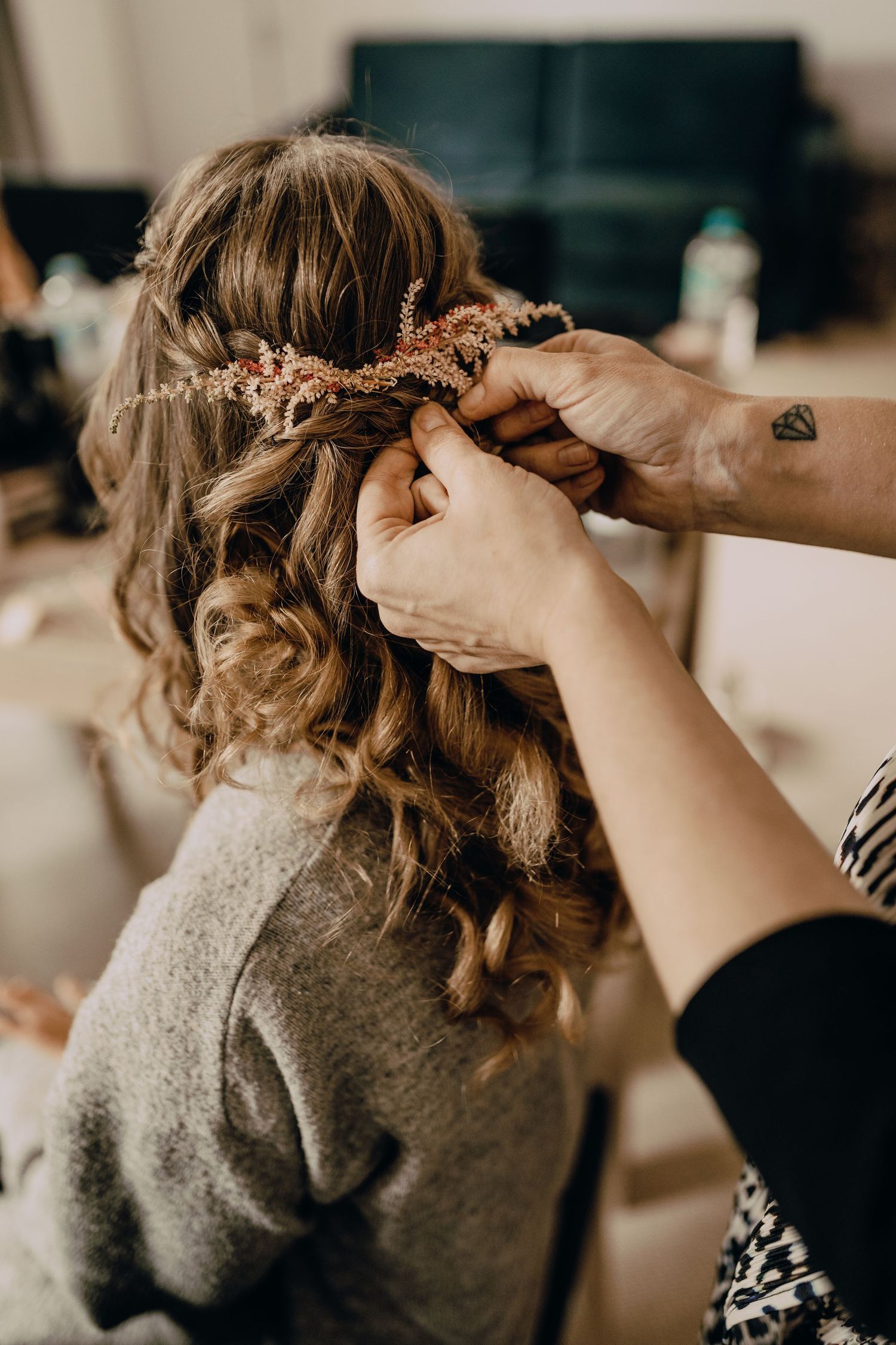 Hairstylist styling curled hair with professional tools during wedding preparation.