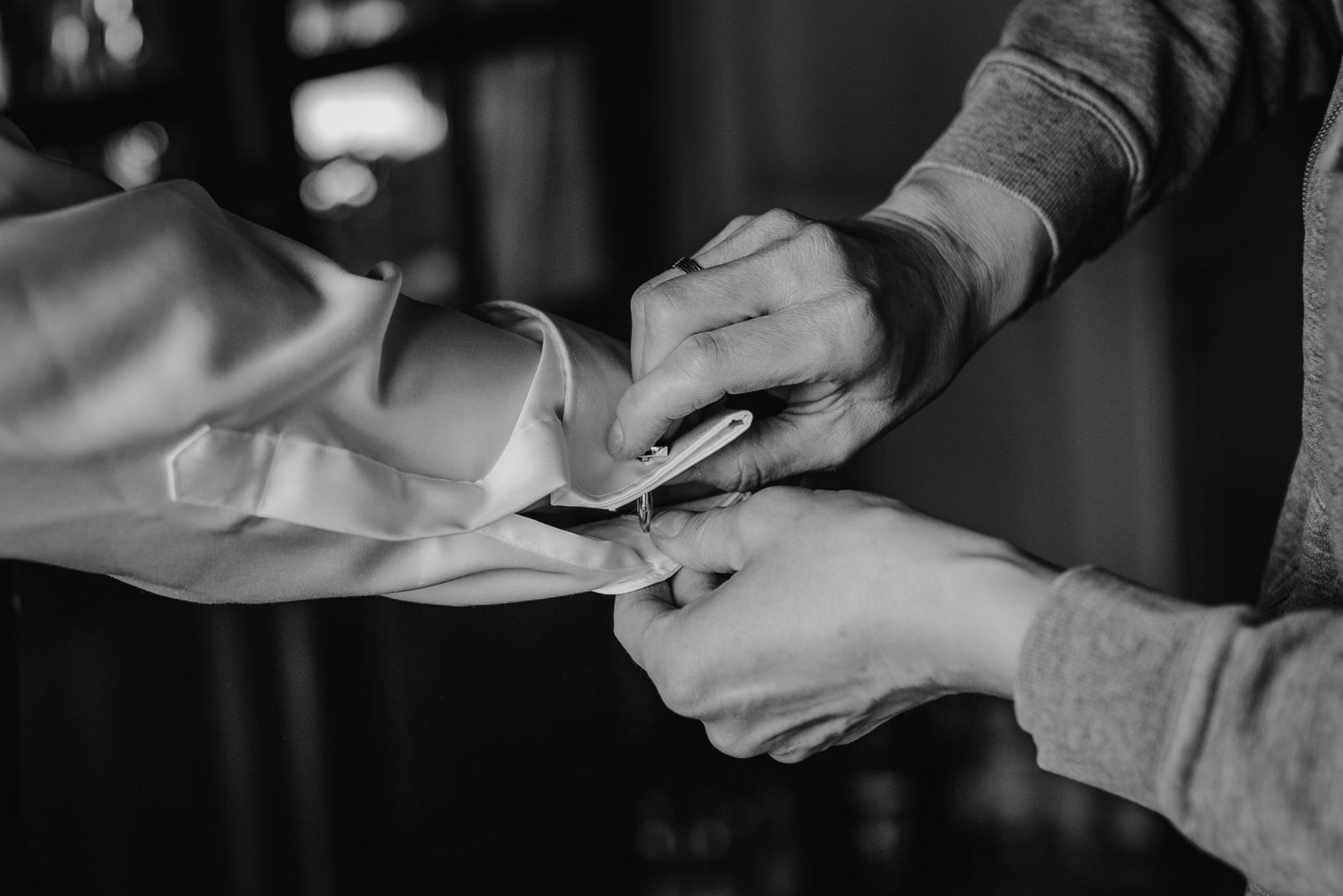 Close up of hands passing documents and signing papers on a dark table surface.