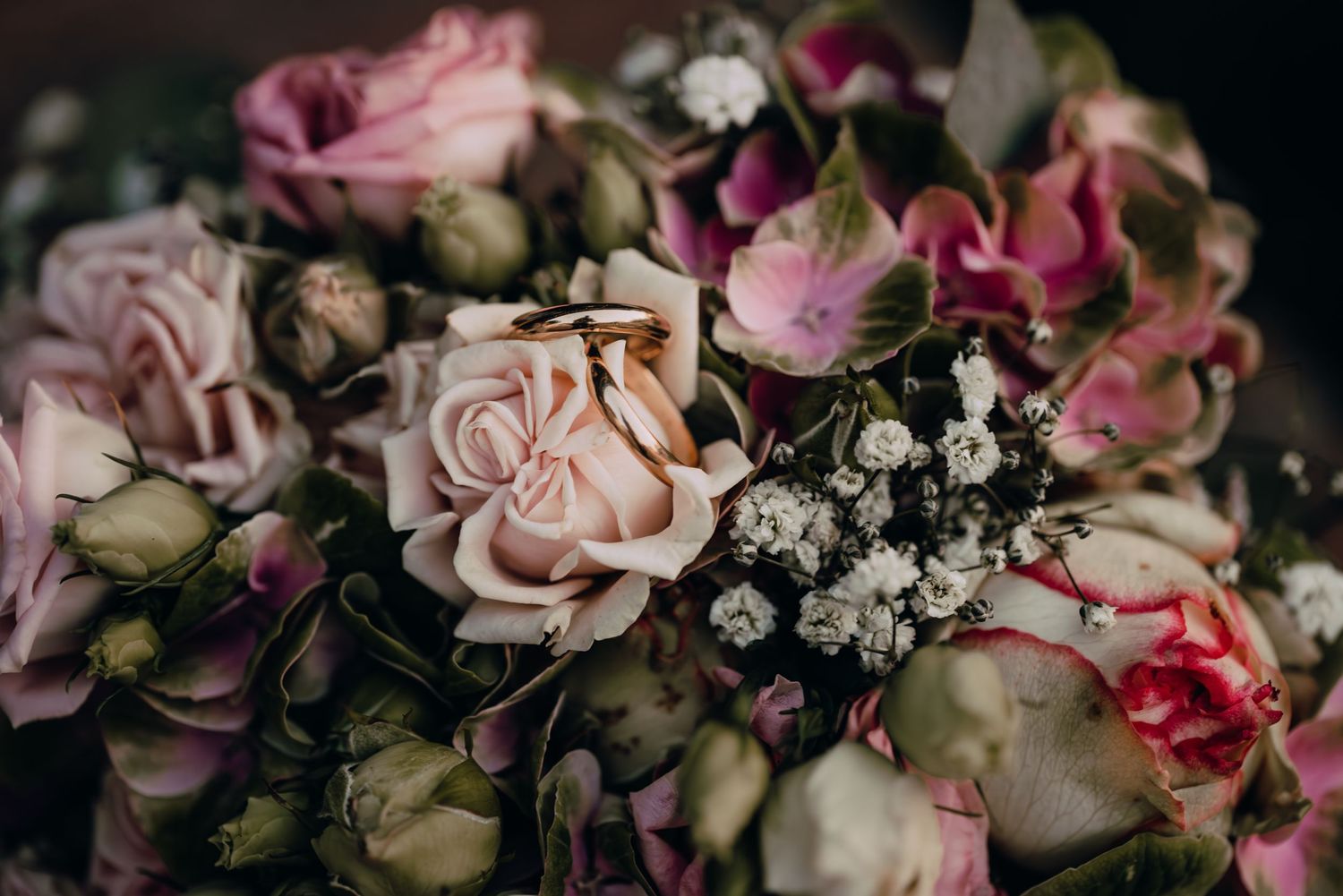 Romantic pastel pink and white roses with small white baby's breath flowers arranged in a lush floral display.
