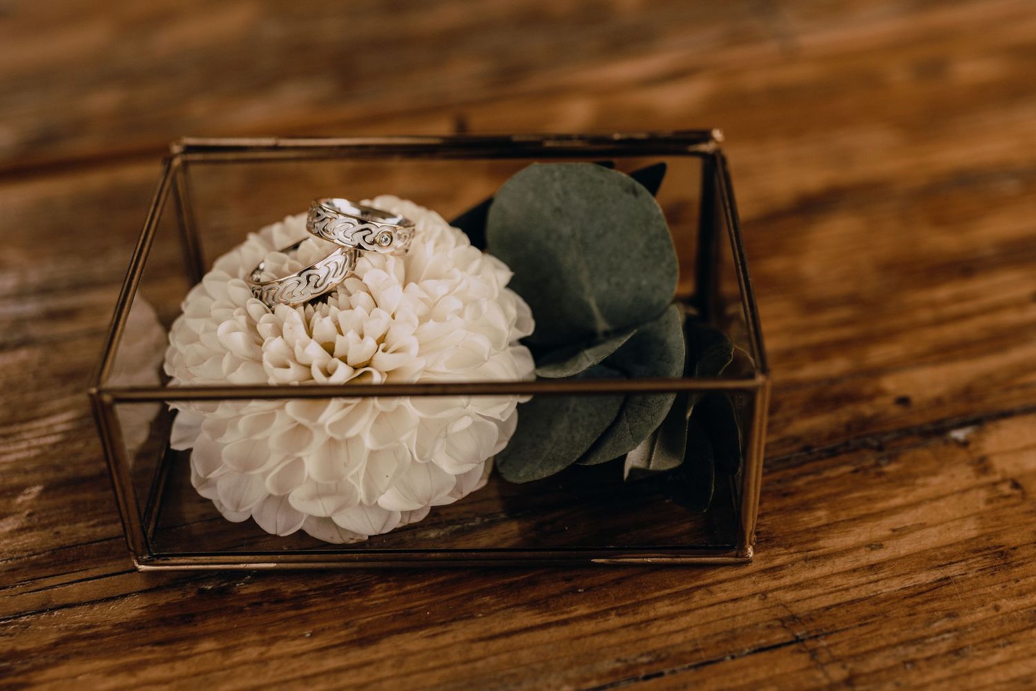 Crystal geodes displayed in dark wooden boxes on a rustic wooden table.