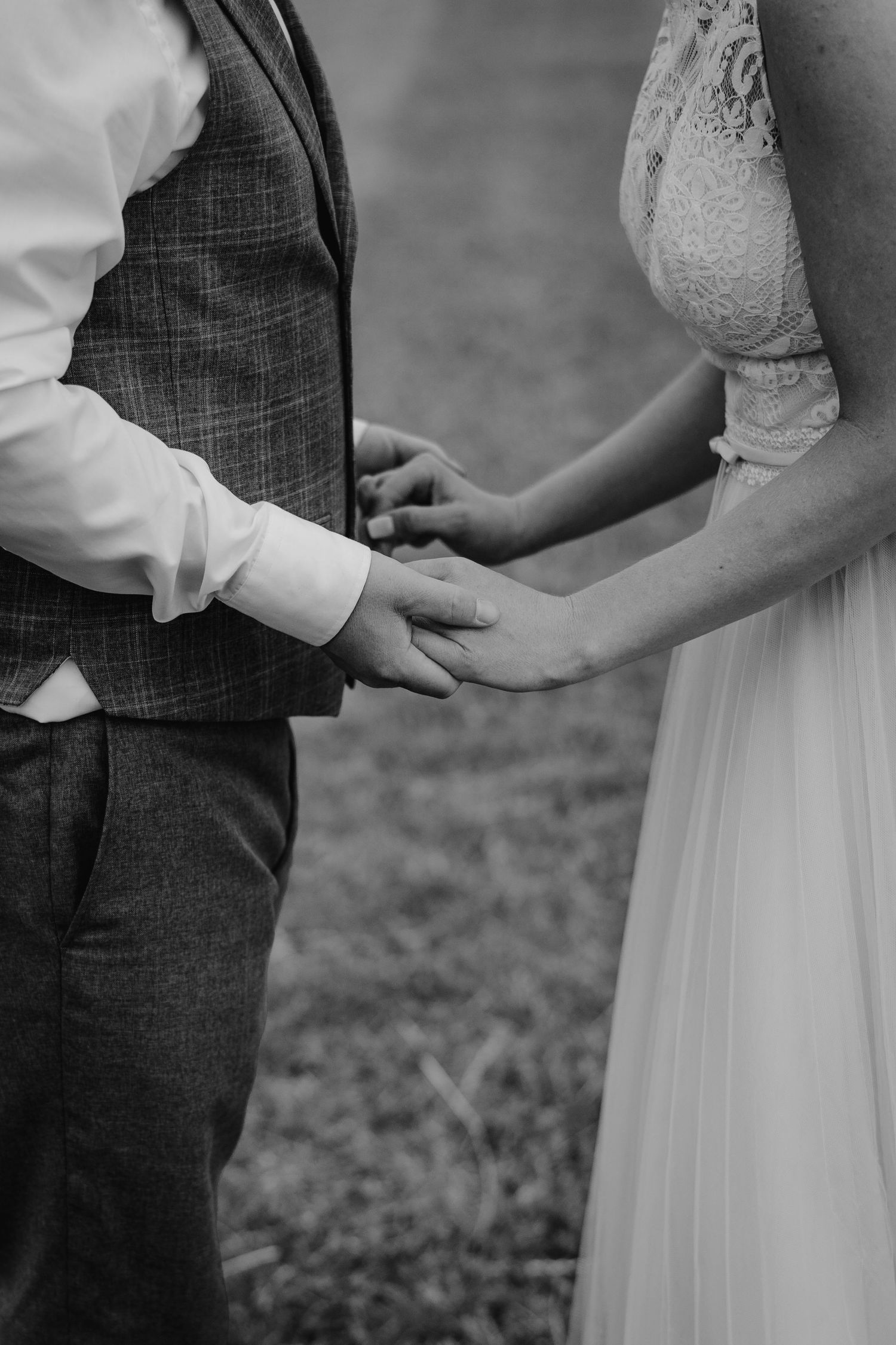 A series of black and white wedding photos showing tender hand holding moments between a bride in white and groom in a vest.