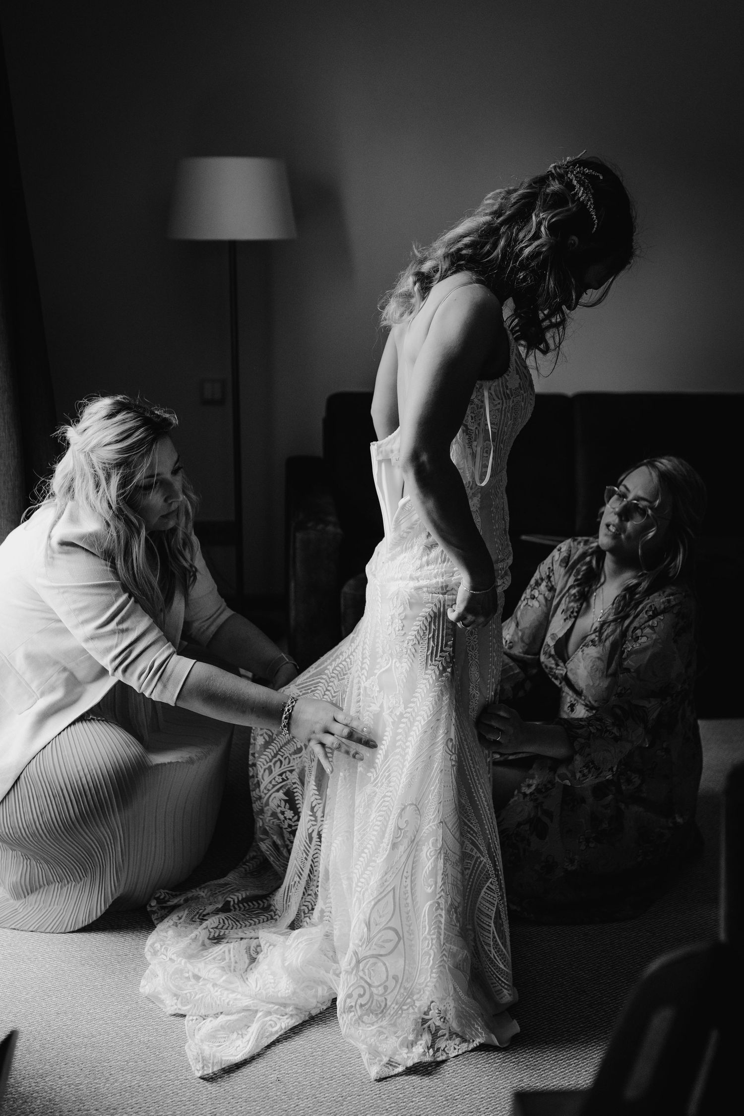 A wedding dress fitting session in progress with lace details being adjusted.