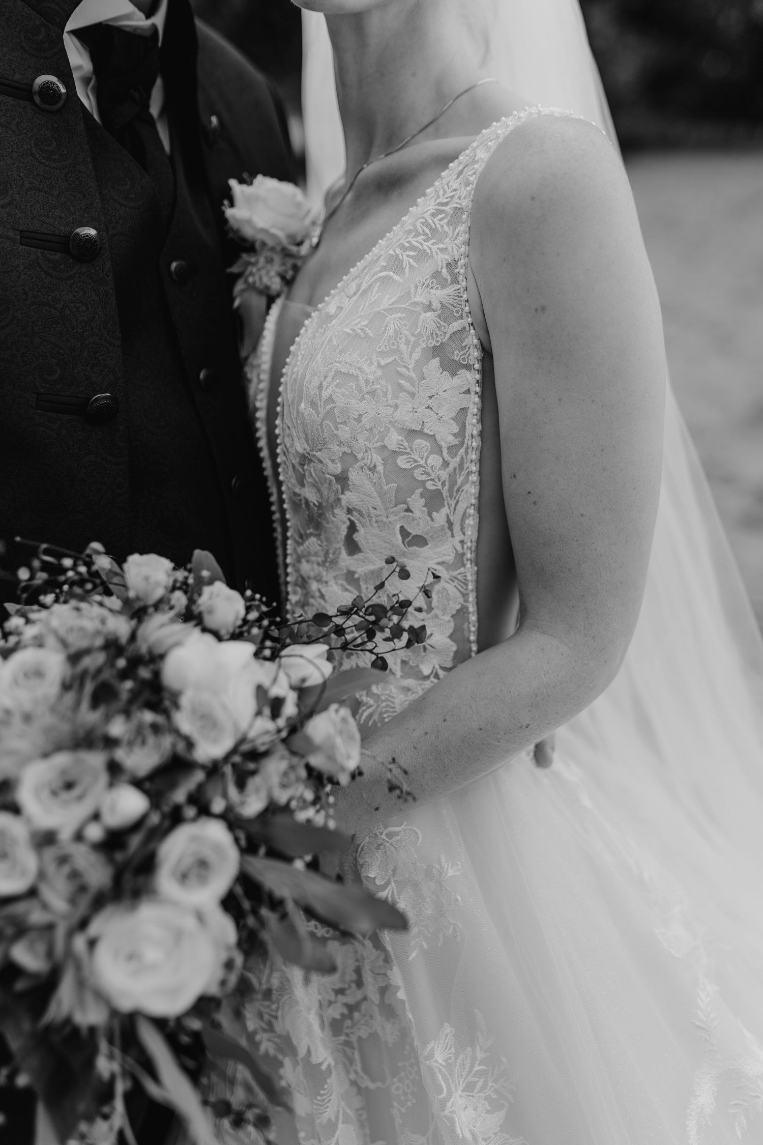 Black and white wedding detail photographs showcase an elegant lace bridal gown and white floral bouquet in close-up views.