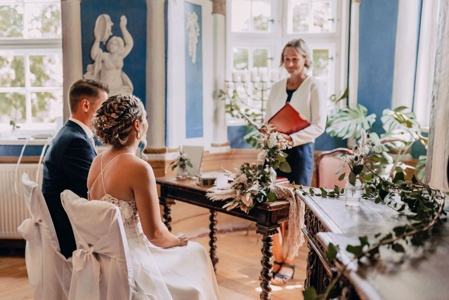 Elegant wedding reception in a bright room with classic decor and floral arrangements on windowsills.