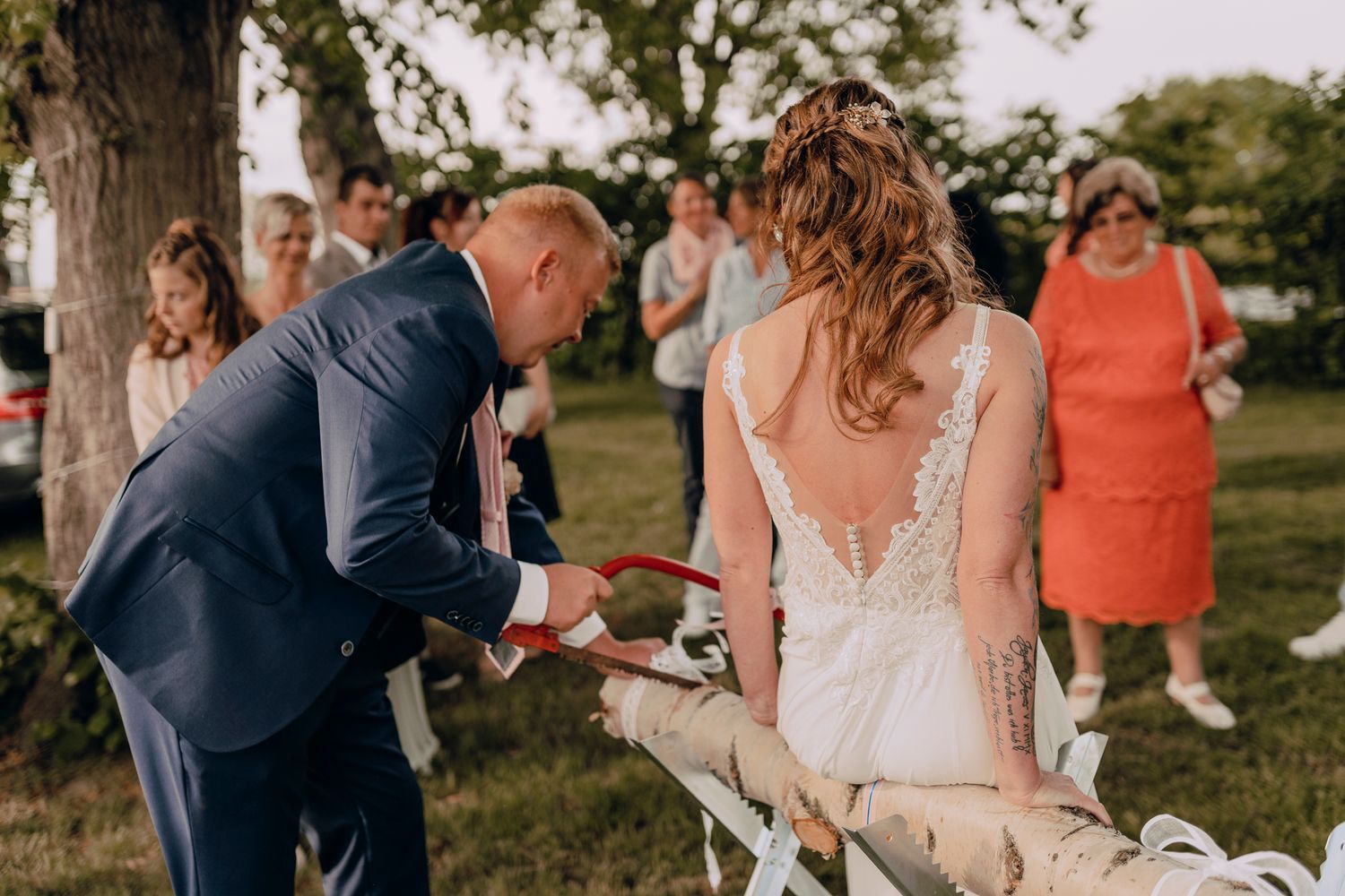 A couple shares a sweet moment with their dog outdoors during a wedding ceremony on a sunny day.