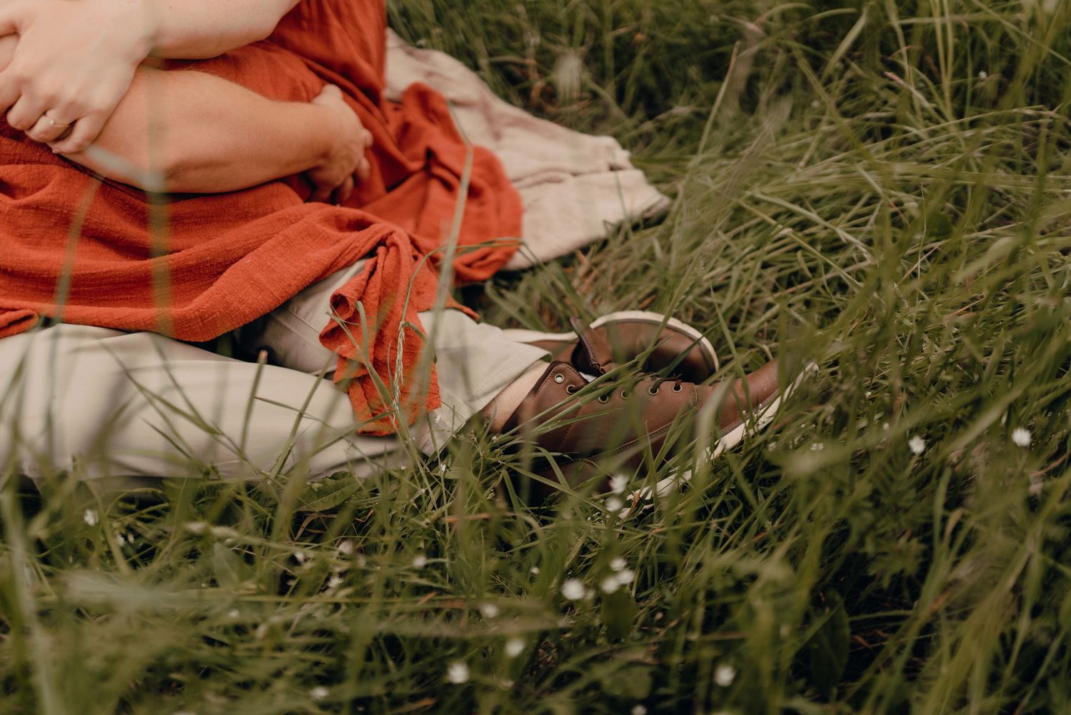 Couple sitting close together in a grassy meadow on a warm sunny day.